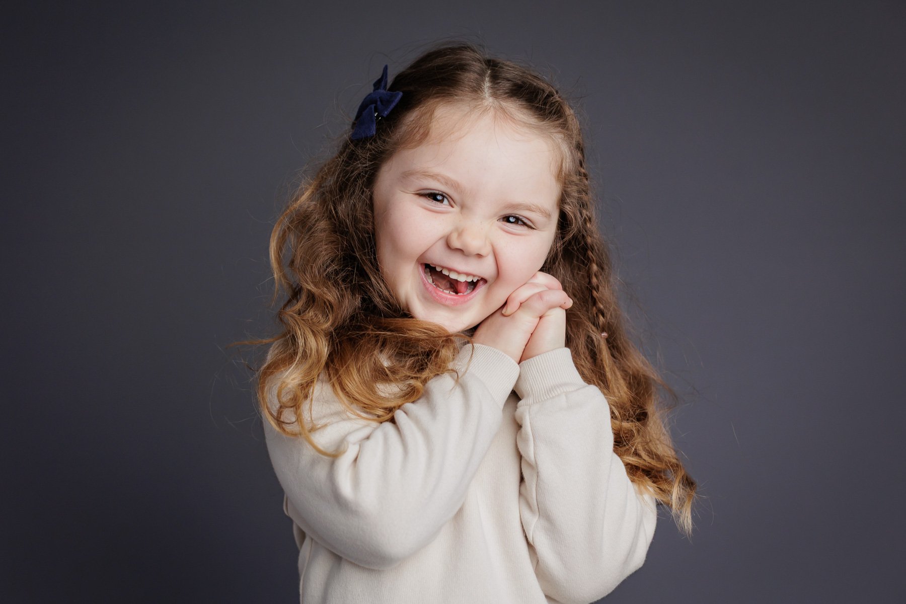preschooler with blond curly hair holding hands and laughing