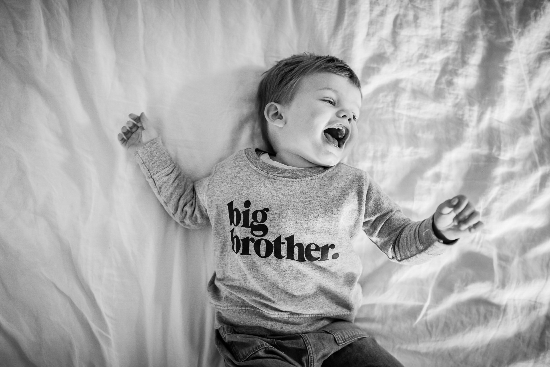 monochrome image of big brother laughing during portland newborn photography session.jpg