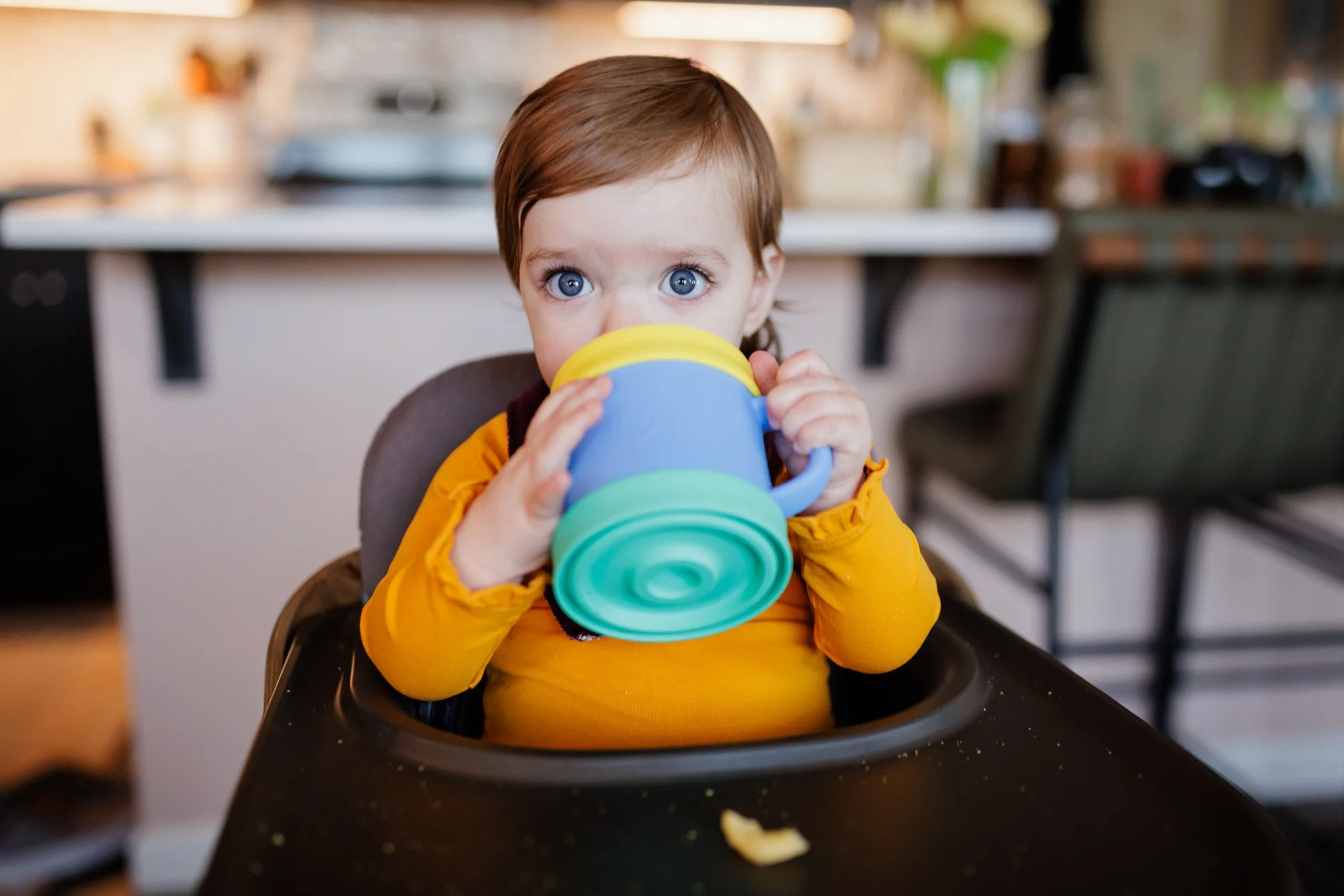 toddler drinking from sippy cup while in high chair