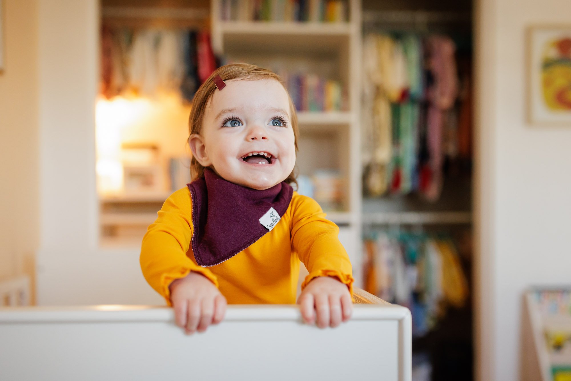 toddler laughing from crib in nursery with closet in background