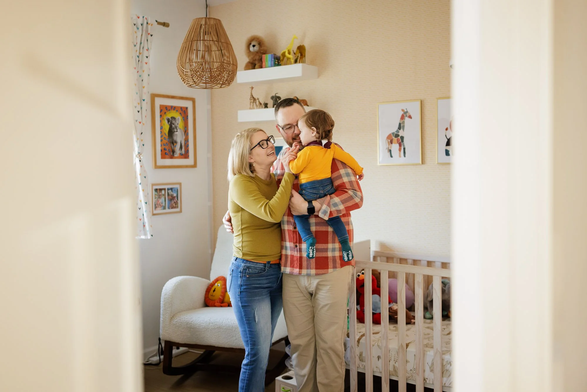 parents holding toddler hanging out in nursery