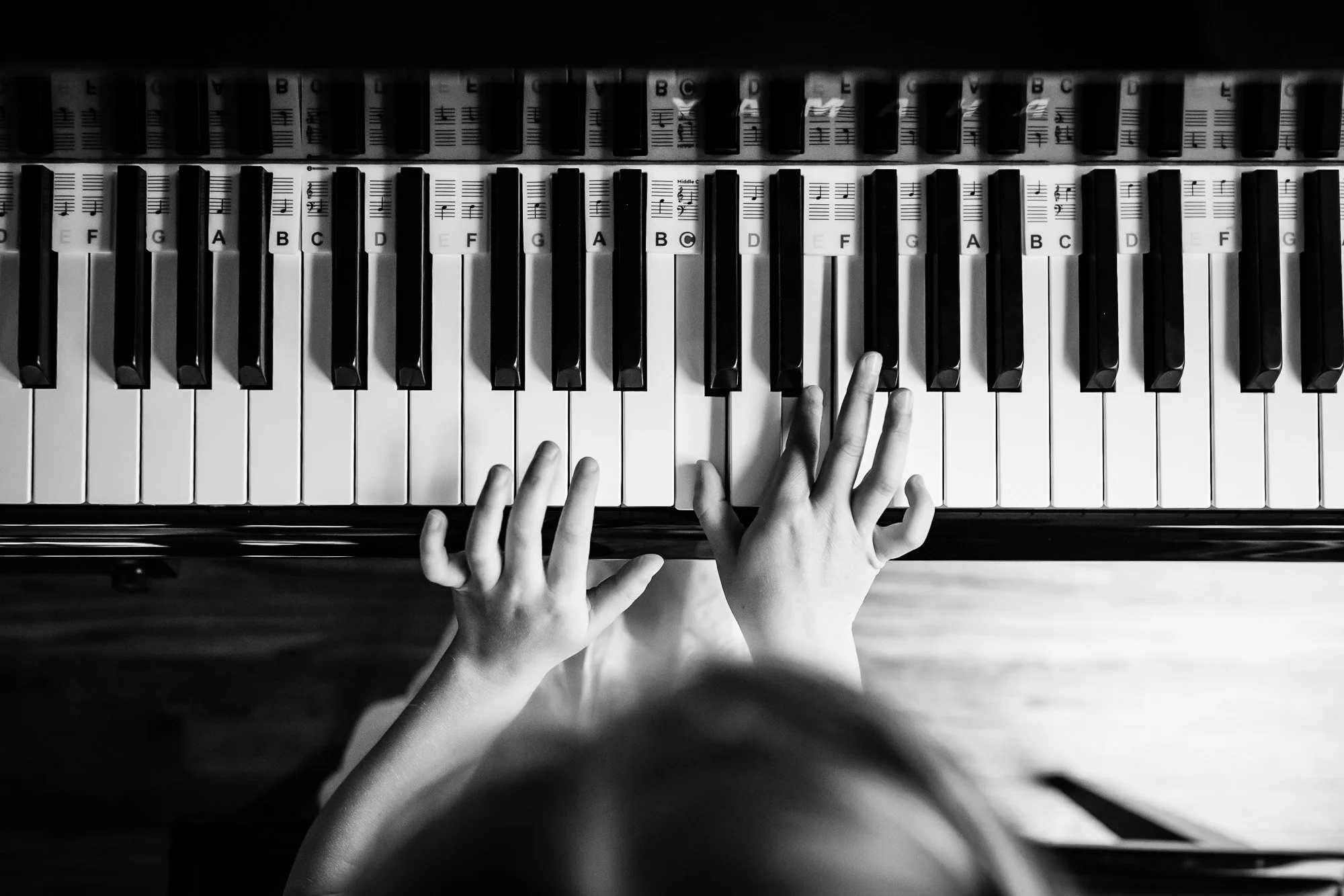 black and white photo taken from overhead of child playing the piano