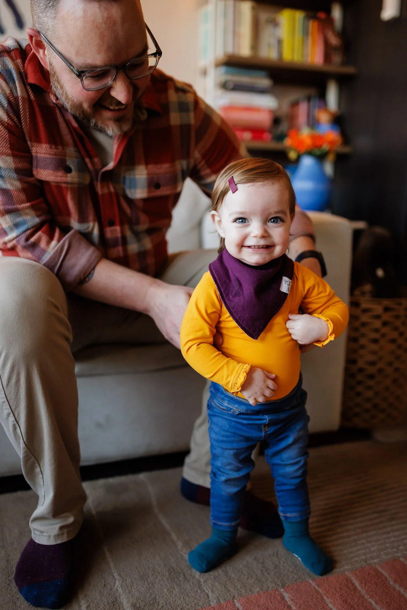 toddler practicing standing in living room with dad
