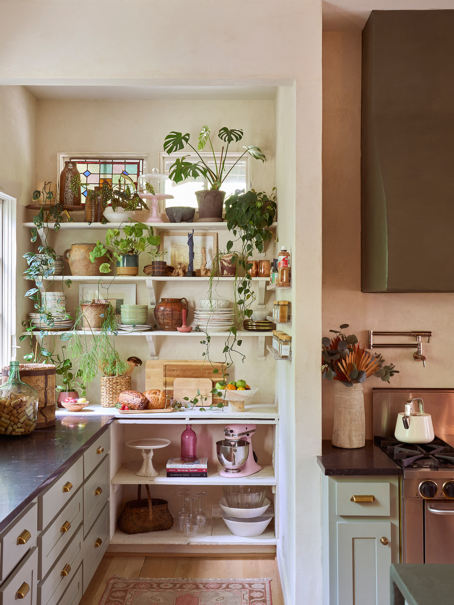A study in curated kitchen styling in Nashville, TN. This project by Branan White Interior Design features a beautiful balance of modern utility and vintage charm. The prep nook includes custom built-in spice racks, textured limewash walls, and a pro