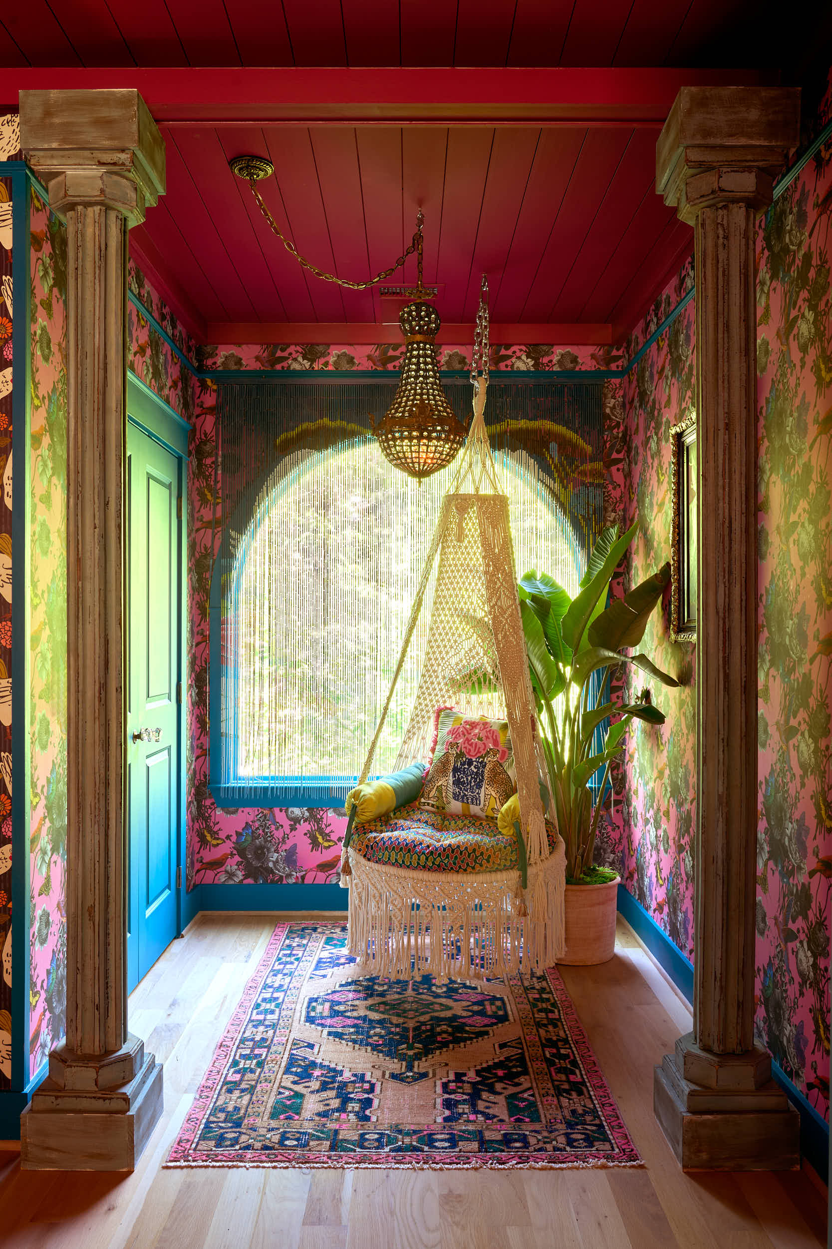 Professional interior photography of a custom-designed lounge in Nashville, TN. This project by Branan White Interior Design showcases a daring pink and teal color palette and architectural depth. The shot features a crystal empire chandelier swagged