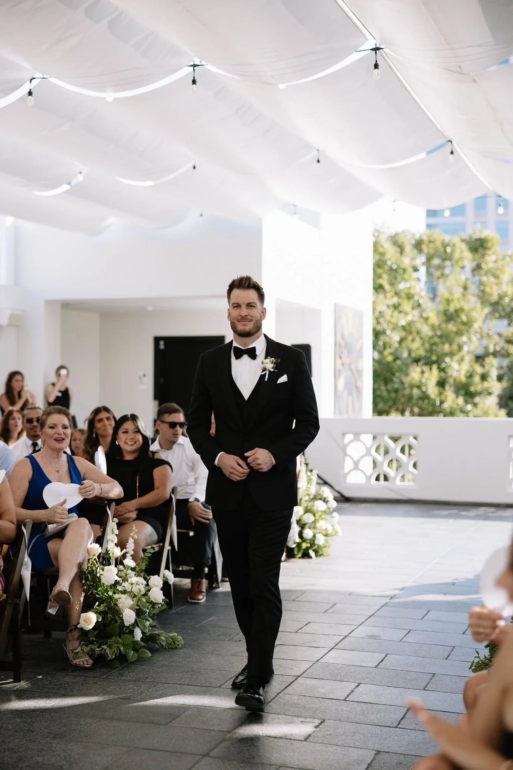 An elegant all-white palette transformed Blanco Urban Venue into a chic urban oasis for Bianca & John’s wedding. Lush roses, towering delphiniums, and touches of soft greenery lined the aisle, creating a bright, modern pathway toward the fireplace al
