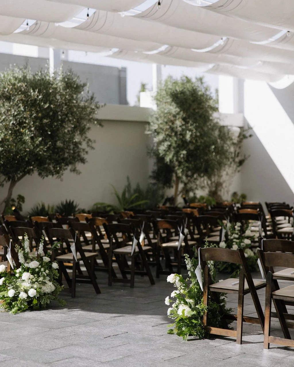 An elegant all-white palette transformed Blanco Urban Venue into a chic urban oasis for Bianca & John’s wedding. Lush roses, towering delphiniums, and touches of soft greenery lined the aisle, creating a bright, modern pathway toward the fireplace al