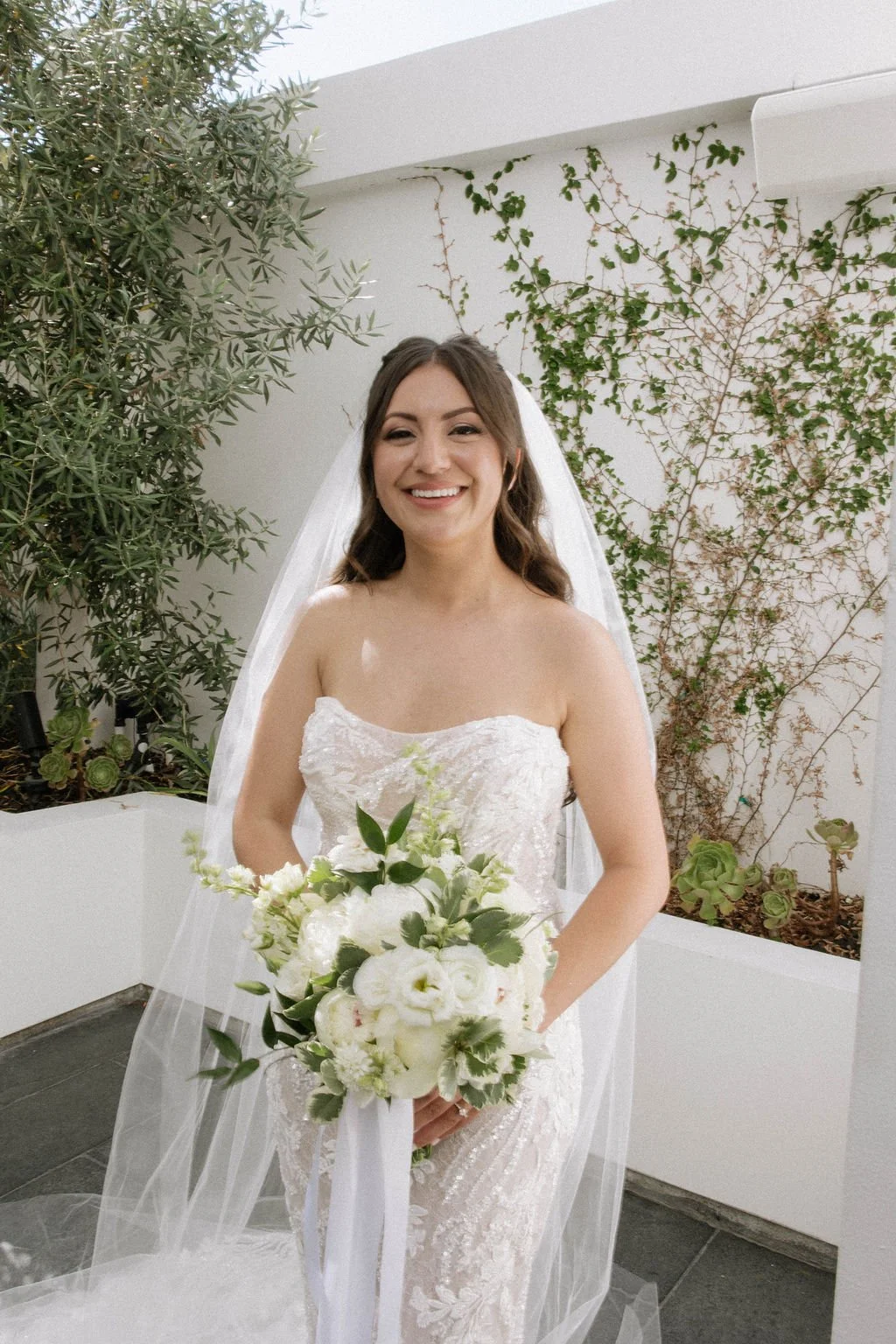 An elegant all-white palette transformed Blanco Urban Venue into a chic urban oasis for Bianca & John’s wedding. Lush roses, towering delphiniums, and touches of soft greenery lined the aisle, creating a bright, modern pathway toward the fireplace al