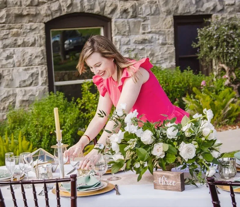 The owner of an events company, one of our valued partners of The Flowers Valley, elegantly setting up a table with lush white florals for a beautiful outdoor event.