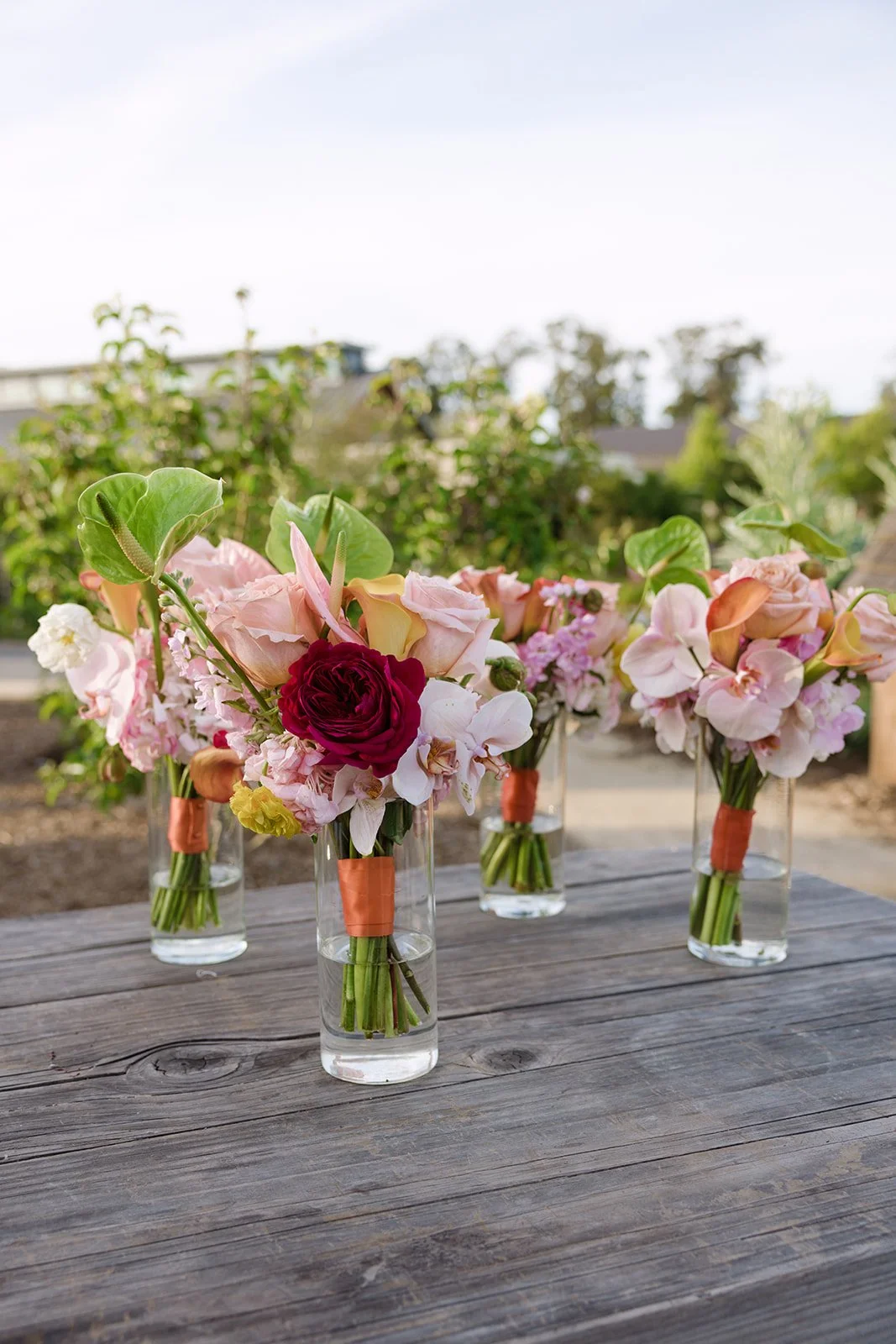 Vibrant Stanly Ranch wedding featuring bold orange, coral, fuchsia, and yellow wedding flowers. Explore lush bridal bouquets, ceremony floral installations, elevated aisle arrangements, and colorful reception centerpieces designed with premium blooms