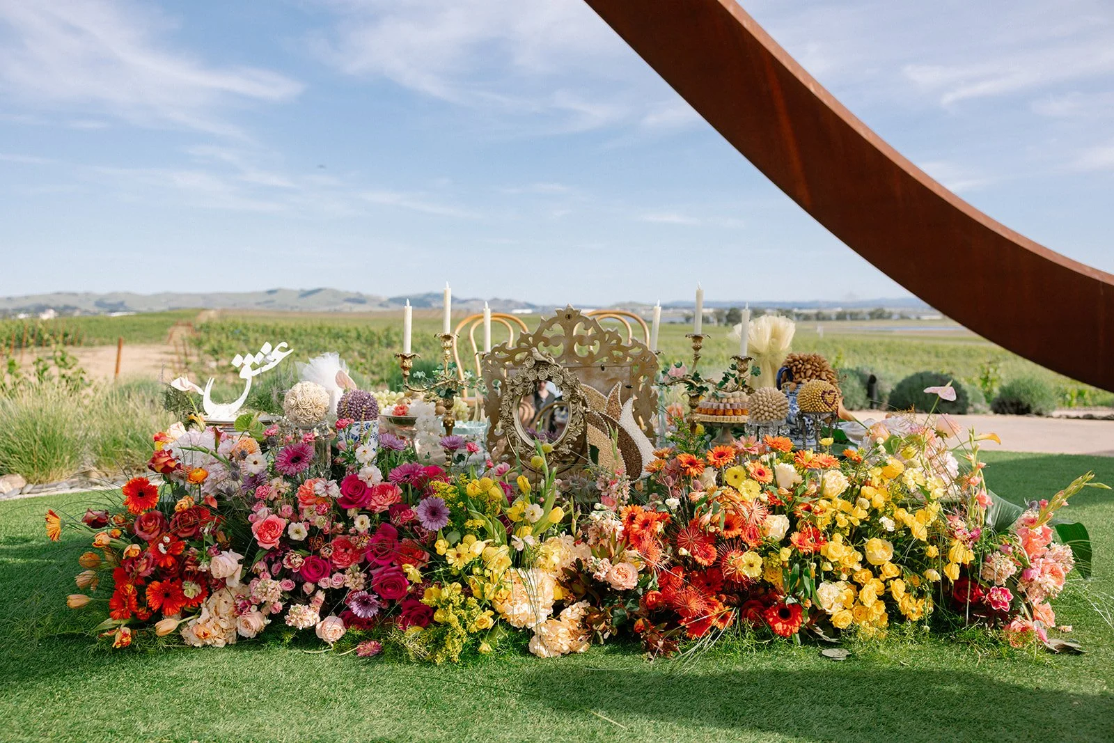 Vibrant Stanly Ranch wedding featuring bold orange, coral, fuchsia, and yellow wedding flowers. Explore lush bridal bouquets, ceremony floral installations, elevated aisle arrangements, and colorful reception centerpieces designed with premium blooms