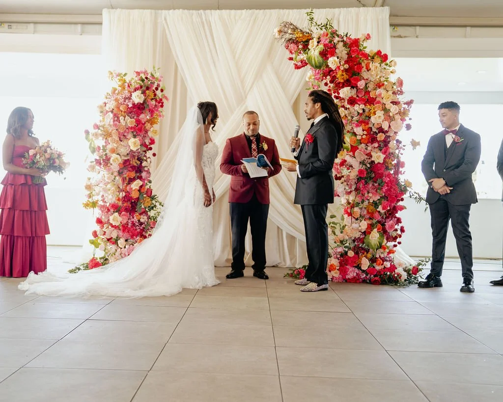 Bold Skyline Events SF wedding with rich deep raspberry, olive green, orange, burgundy, and pink wedding flowers. Featuring striking bridal and bridesmaid bouquets, ceremony florals, colorful reception centerpieces, lush aisle arrangements, and premi