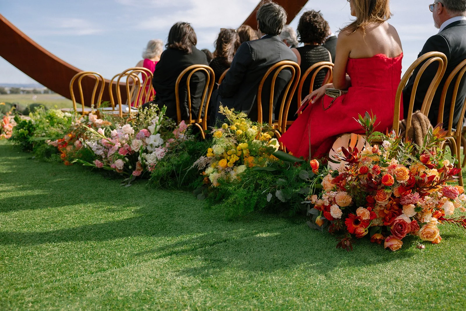 Vibrant Stanly Ranch wedding featuring bold orange, coral, fuchsia, and yellow wedding flowers. Explore lush bridal bouquets, ceremony floral installations, elevated aisle arrangements, and colorful reception centerpieces designed with premium blooms