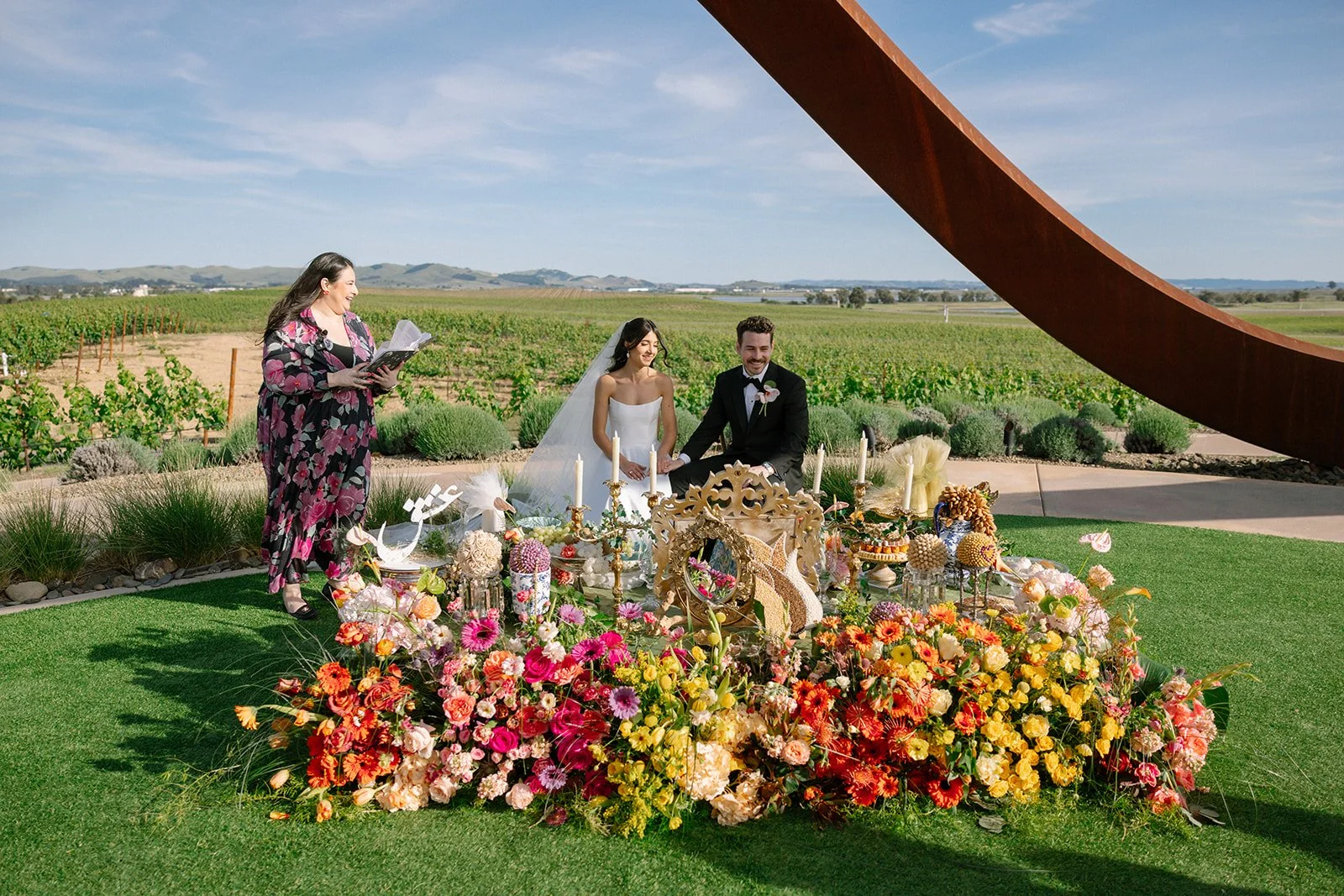 Vibrant Stanly Ranch wedding featuring bold orange, coral, fuchsia, and yellow wedding flowers. Explore lush bridal bouquets, ceremony floral installations, elevated aisle arrangements, and colorful reception centerpieces designed with premium blooms