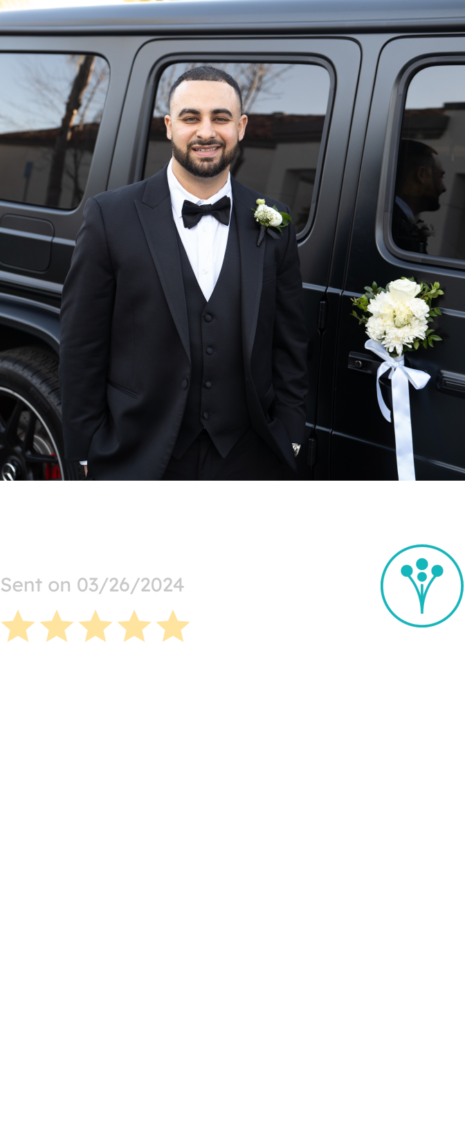 A groom in a sharp black tuxedo smiles beside a black car adorned with white floral decor, showcasing the wedding arrangements designed by a Sonoma County-based florist.
