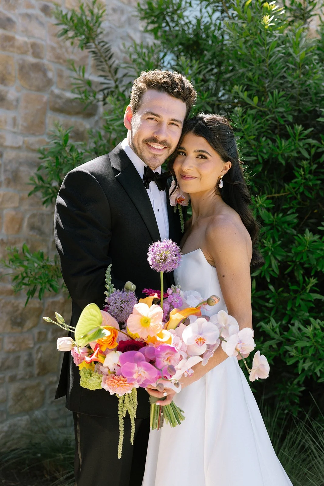 Vibrant Stanly Ranch wedding featuring bold orange, coral, fuchsia, and yellow wedding flowers. Explore lush bridal bouquets, ceremony floral installations, elevated aisle arrangements, and colorful reception centerpieces designed with premium blooms