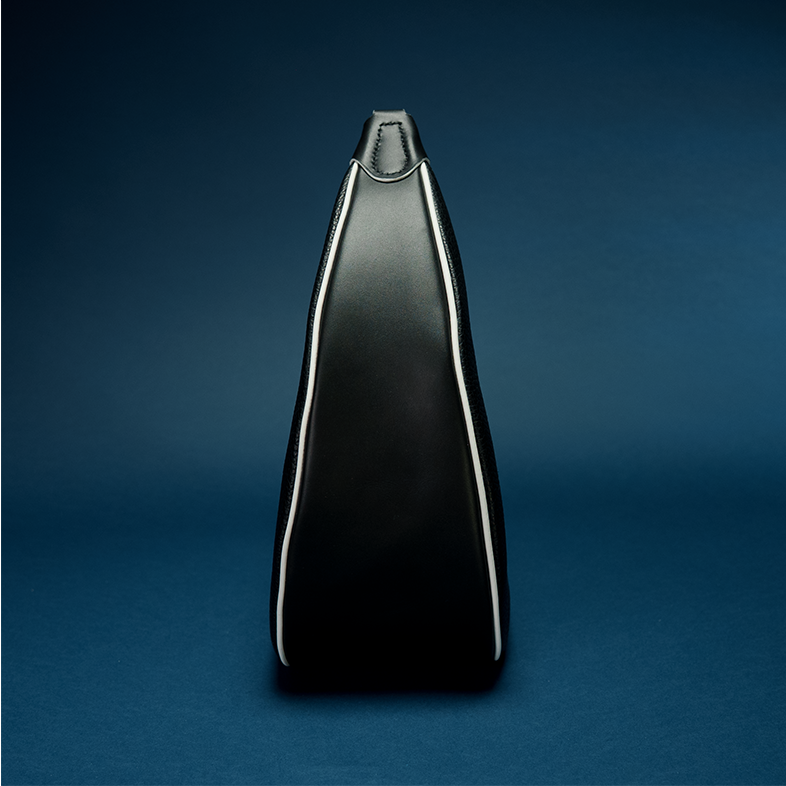 REINA Shoulder Bag in Midnight — pebbled black calf leather crescent silhouette with white piping trim and gunmetal hardware, paired with the RINA La Bori sneaker