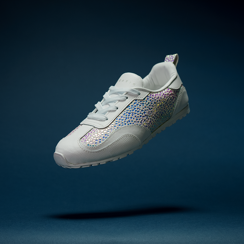 RINA Sneakerina Angelic colorway — white smooth Italian calf leather upper with iridescent suede Duo contrast panel, floating against a dark studio background