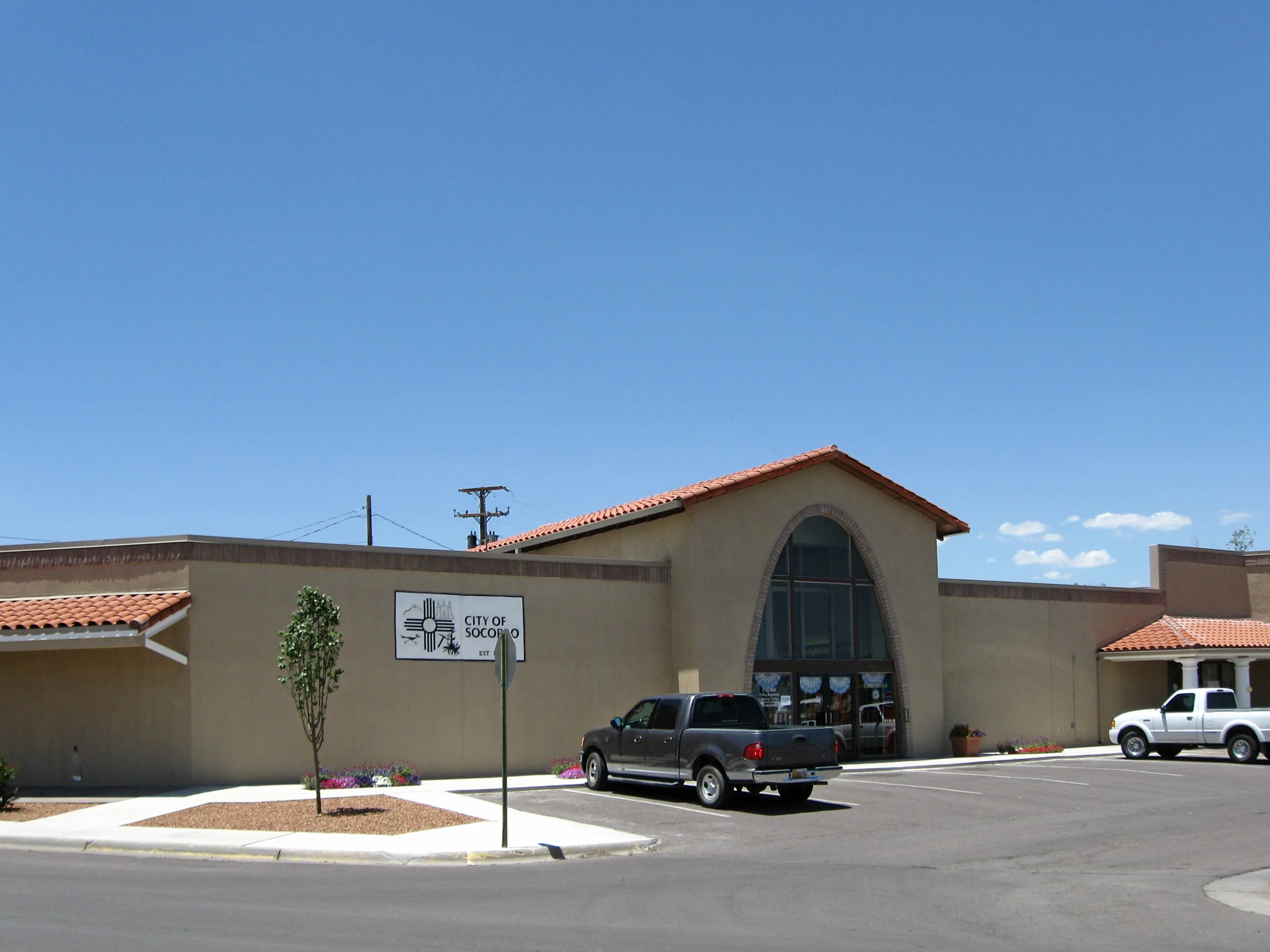 Socorro, New Mexico City Hall, a low southwestern-style adobe civic building under a blue desert sky.