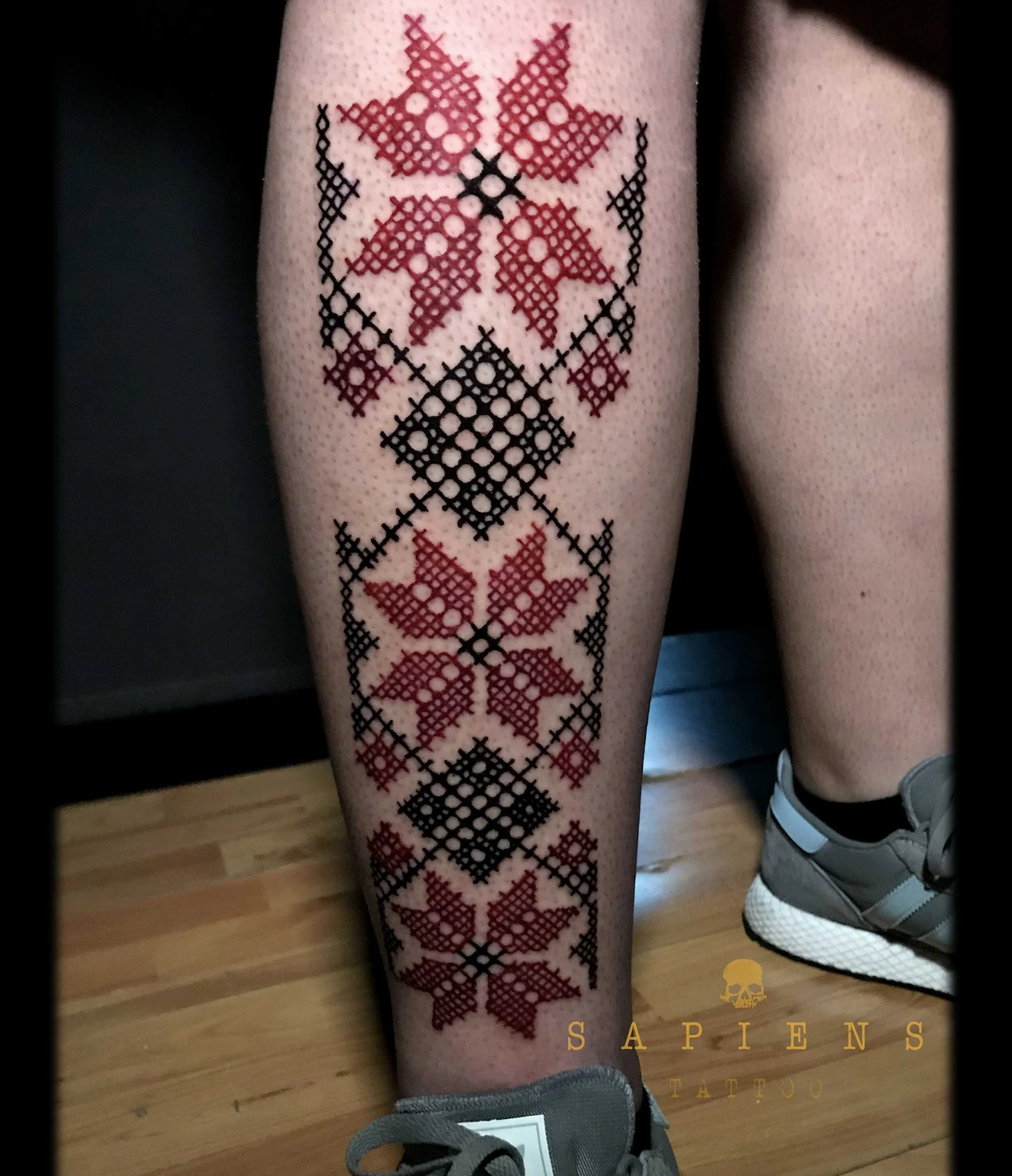 tatuaj geometric pe tibie cu motive traditionale si tus rosu