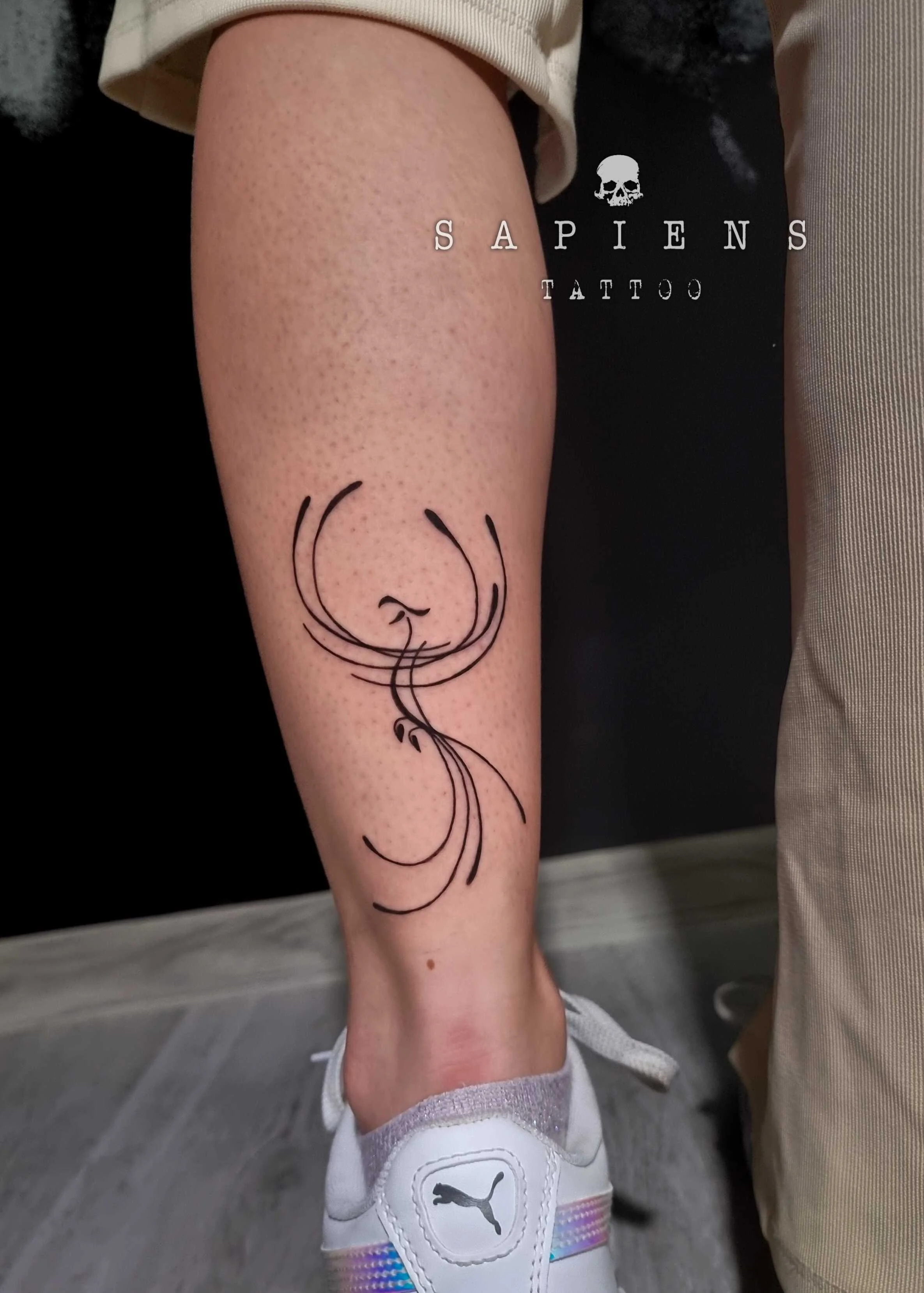tatuaj pe gamba realizat din linii ce reda o pasare phoenix