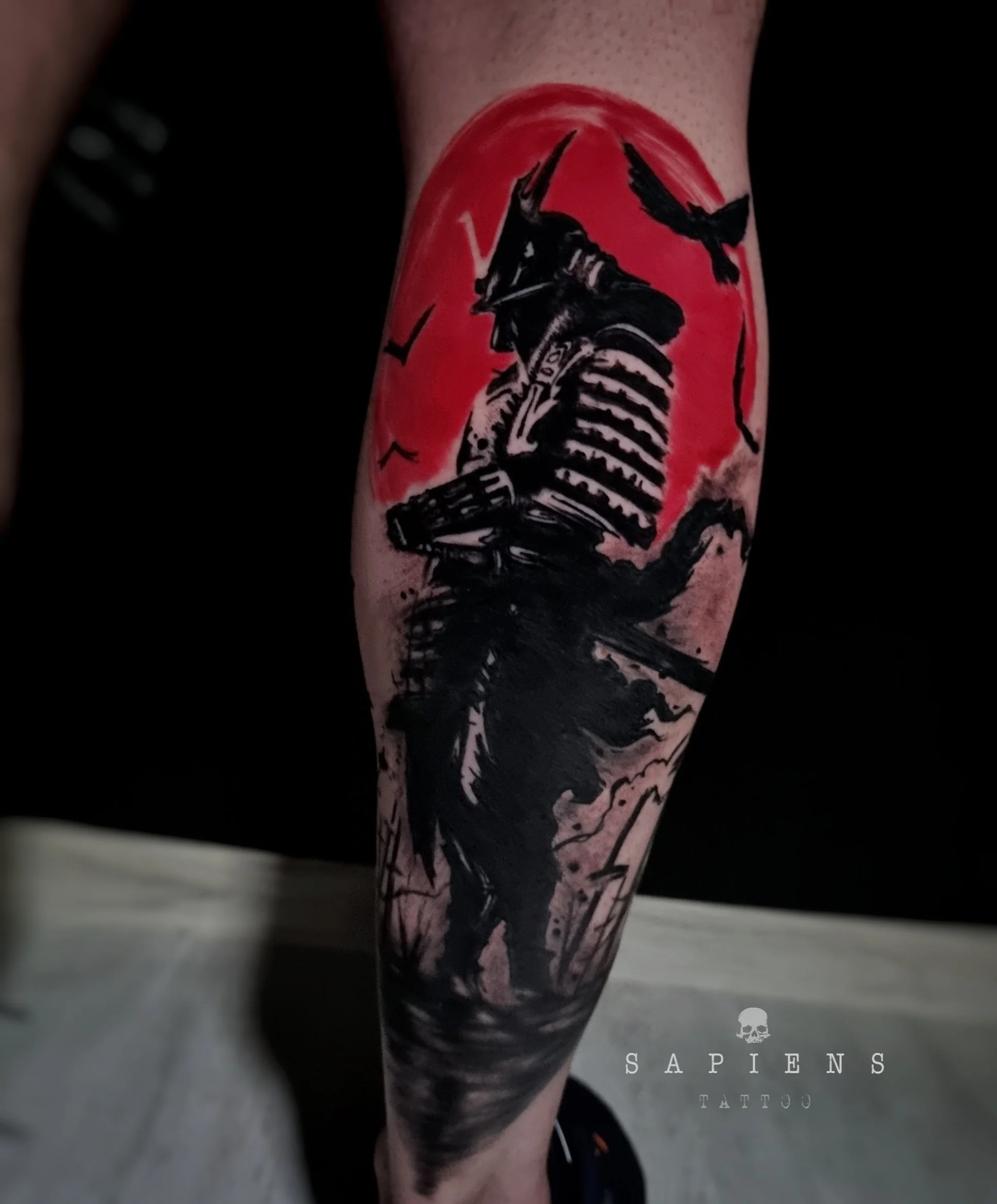 tatuaj pe gamba spate cu un samurai realizat si un fundal abstract cu tus rosu