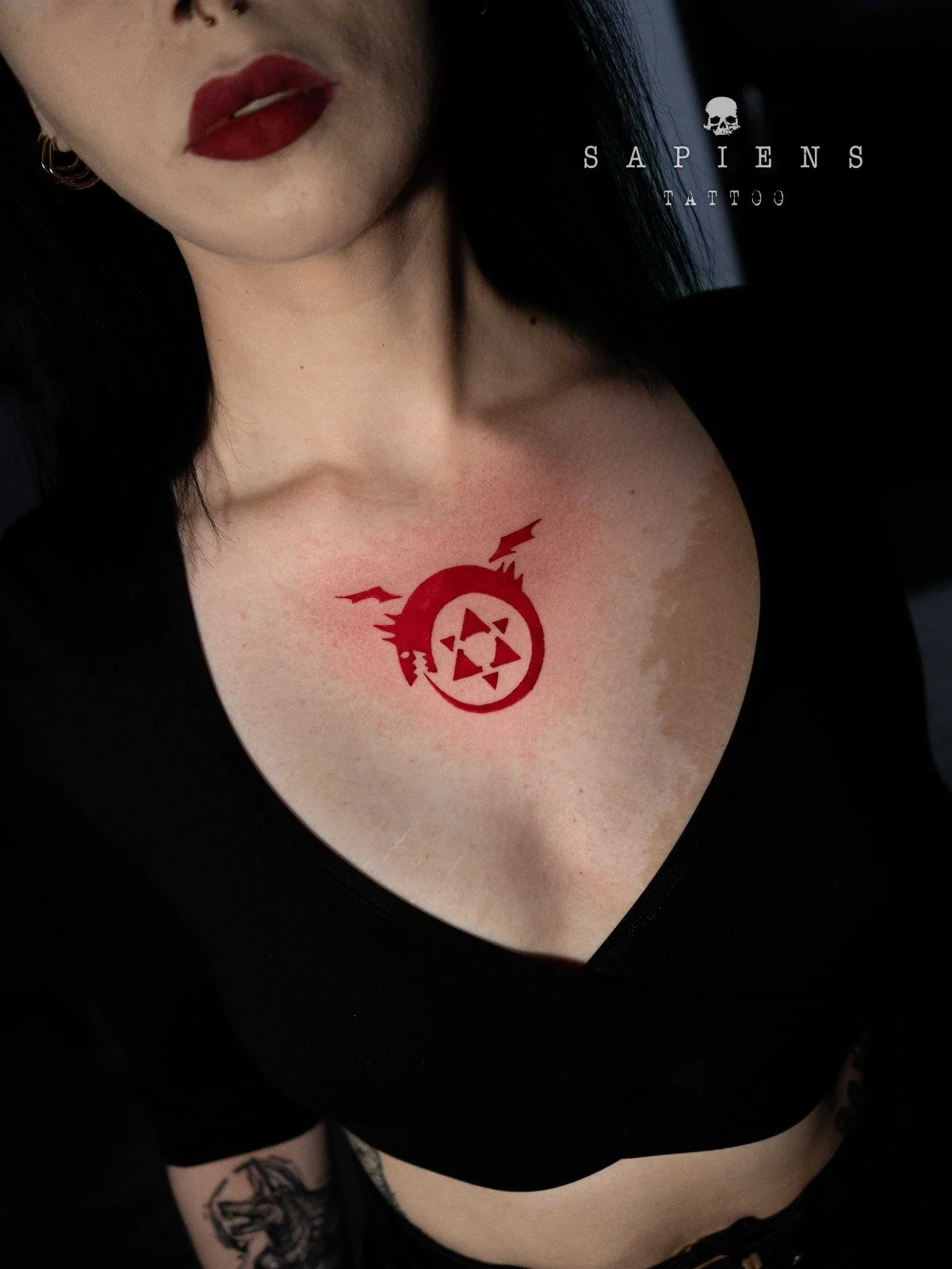 tatuaj centrat pe pieptul unei femei realizat cu tus rosu integral simbolizant un sarpe uroborus