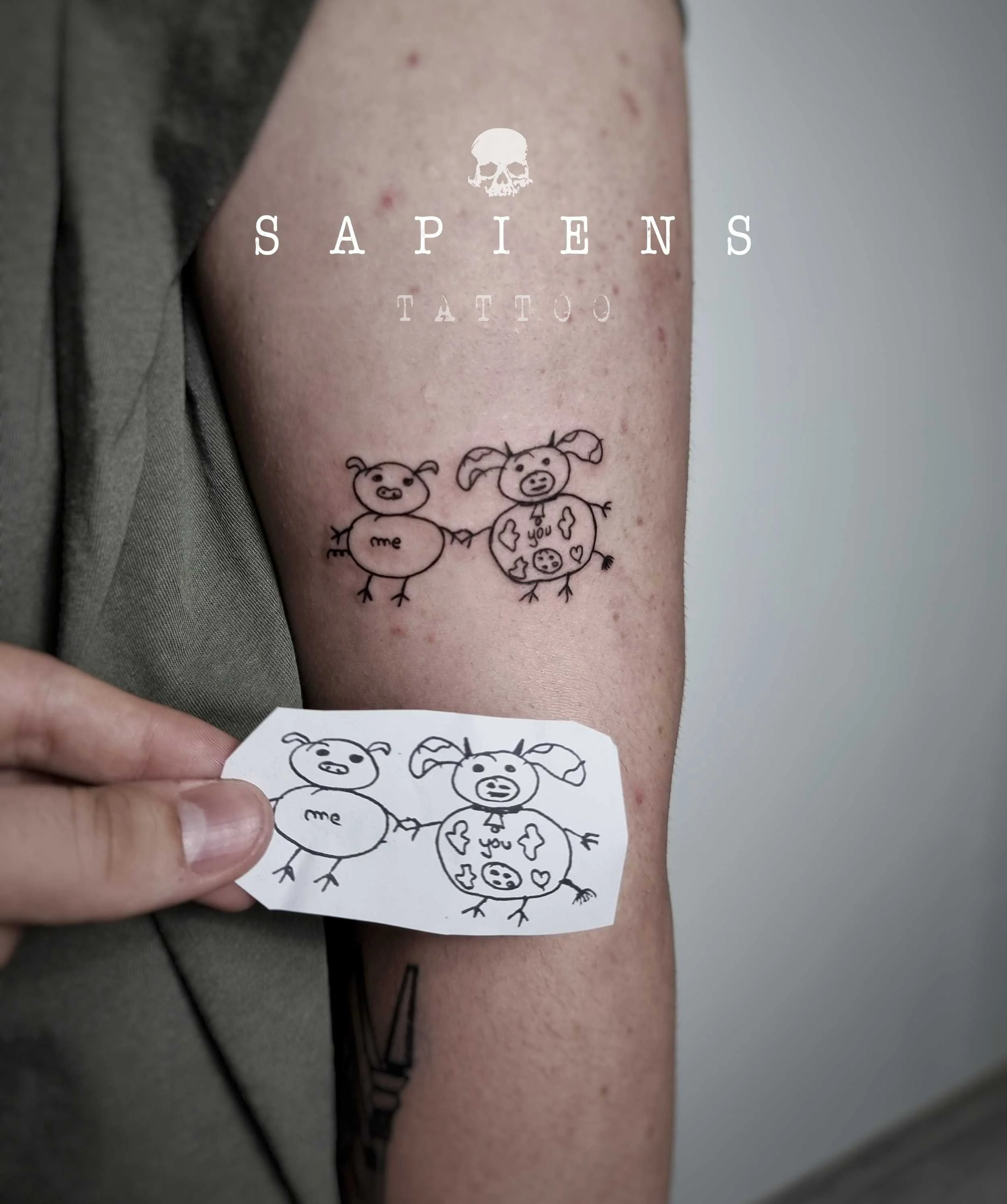 tatuaj pozitionat pe brat zona biceps cu un desen facut de mana cu forma de un purcelus si o vacuta ce simbolizeaza prietenia dintre doua persoane