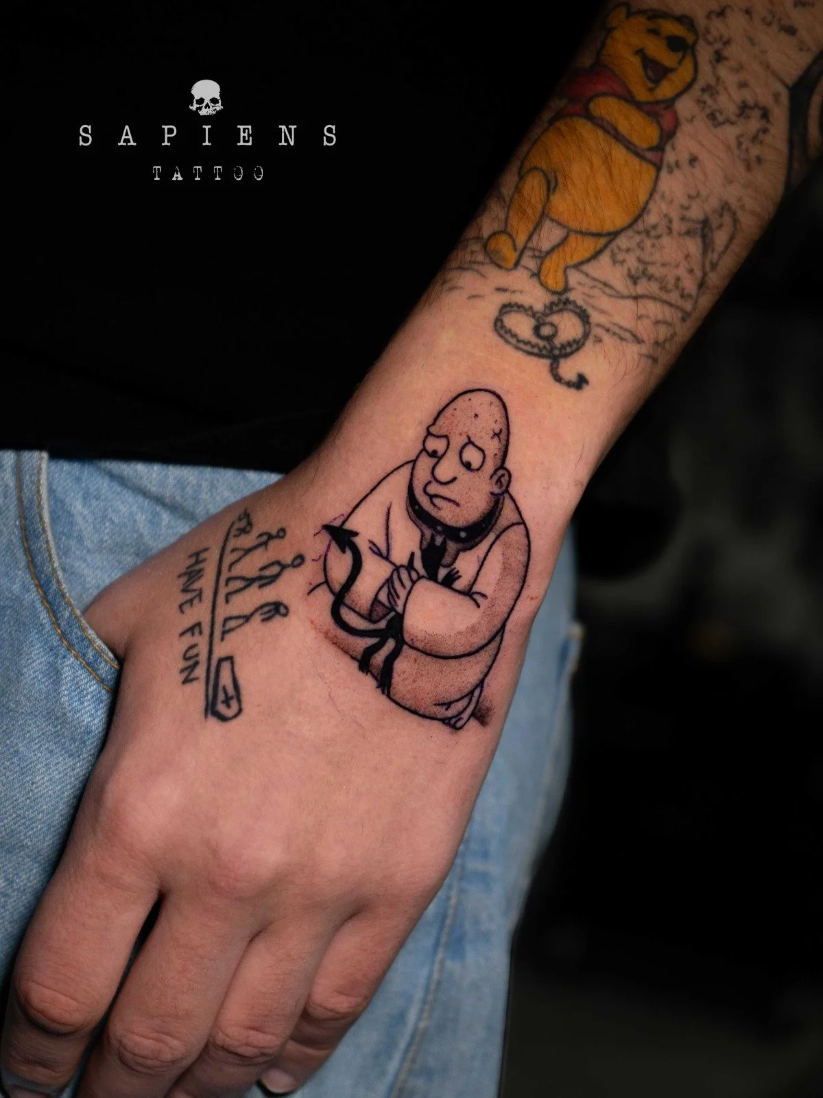 tatuaj pe mana aproape de inchietura cu scris si un desen amuzant