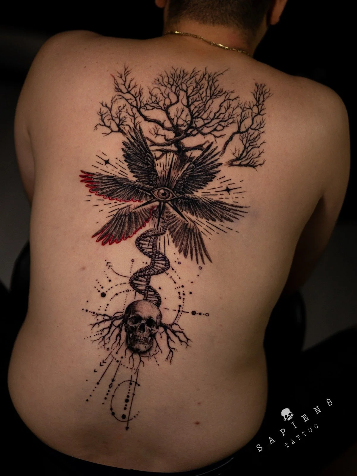 tatuaj mare pe spate cu copacul vietii un craniu si alte elemente decoartive facut in stil abstract si realistic