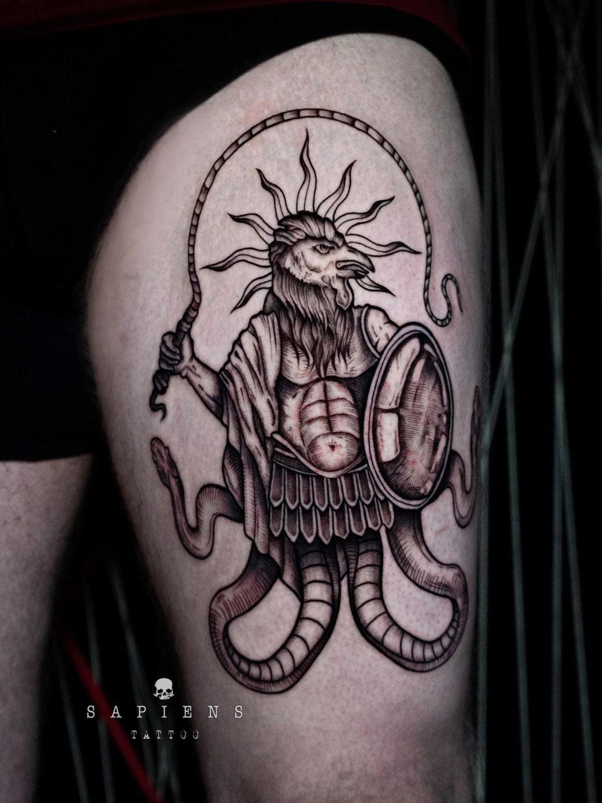 tatuaj mare pe o pulpa cu un grifon ce tine un bici in mana