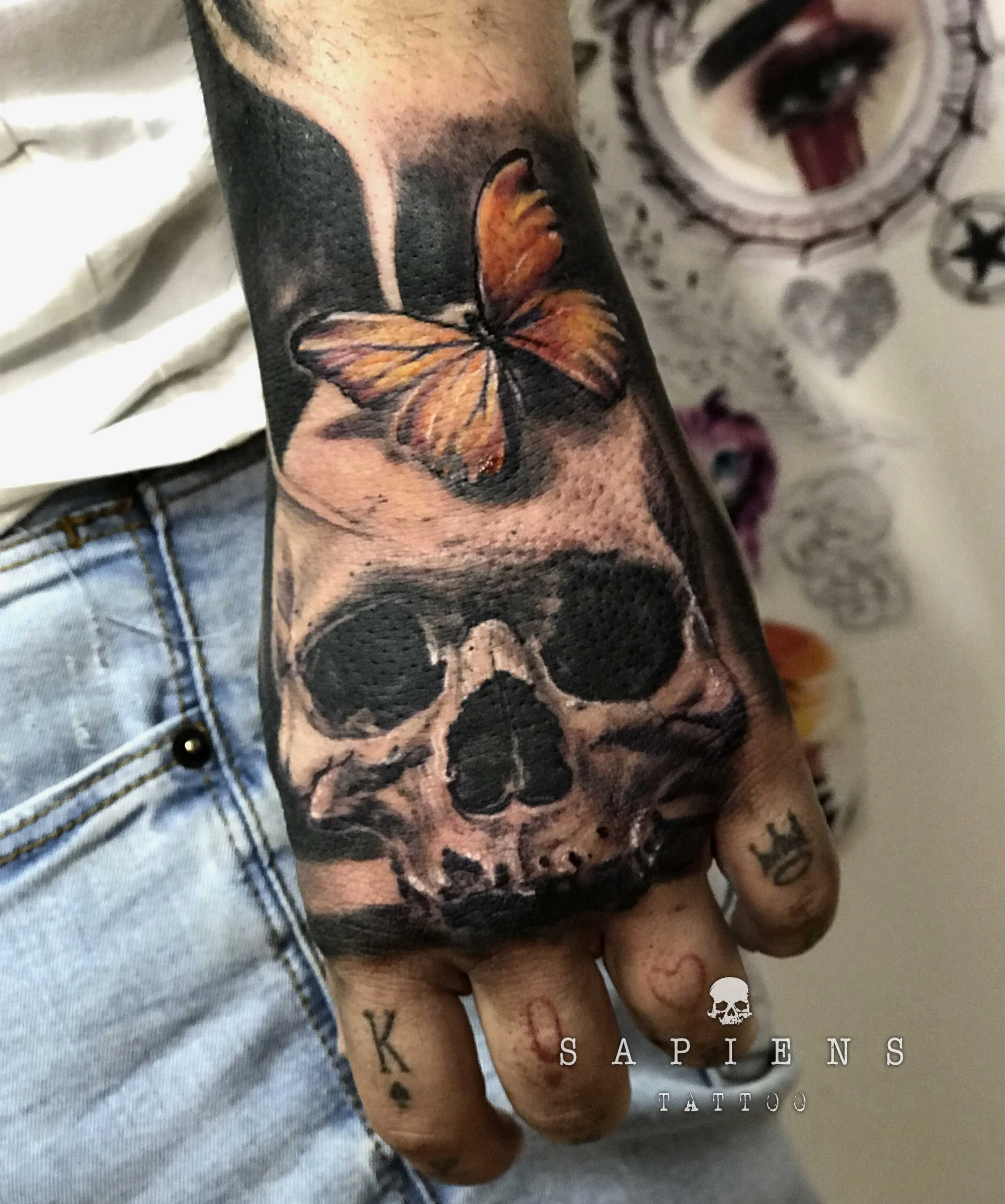 tatuaj pe pumnul unui barbat cu un craniu si un fluture color
