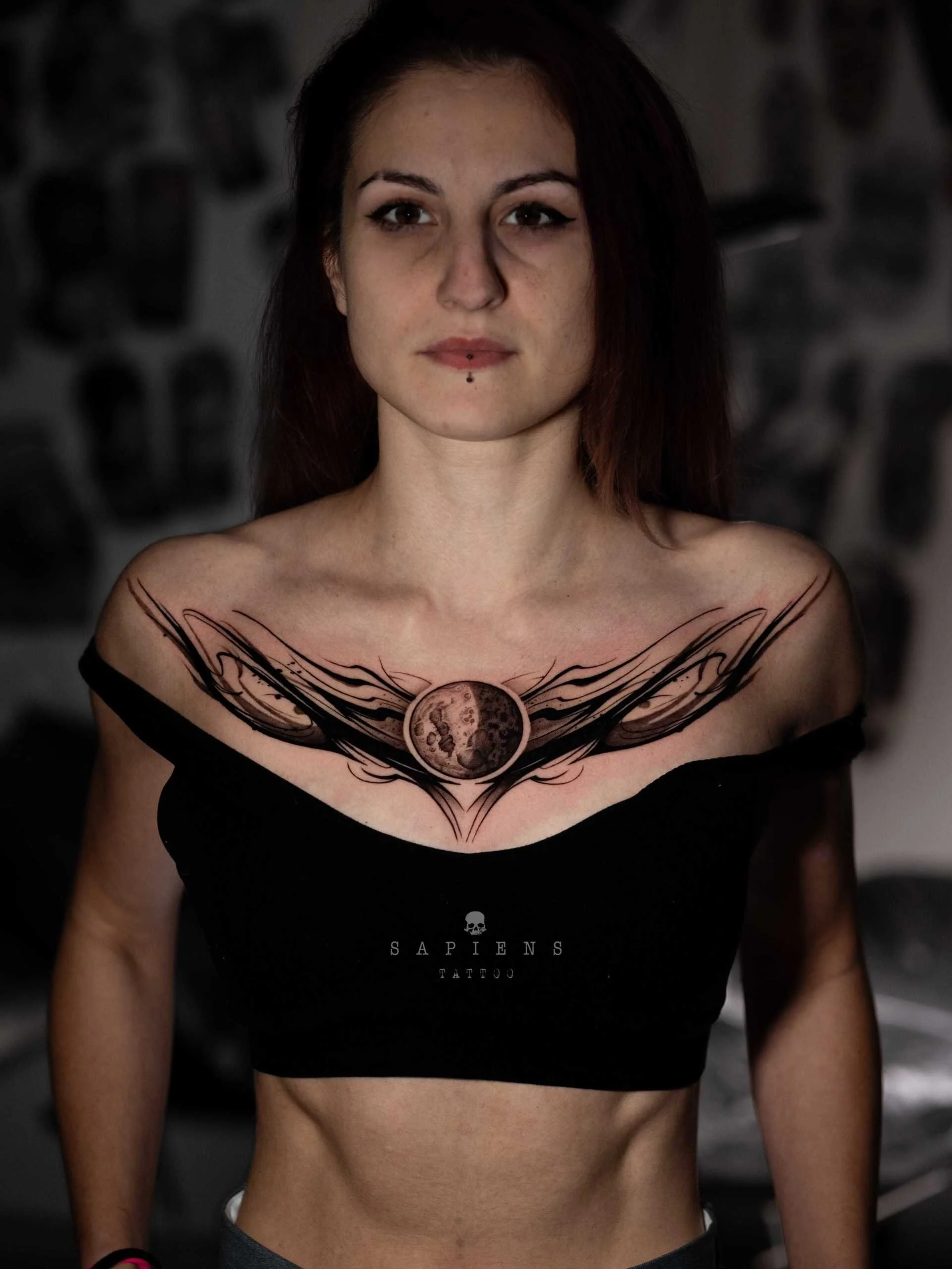 tatuaj pentru femei si barbati cu luna si motive abstracte tatuate pe pieptul unei femei de la un umar la celalalt