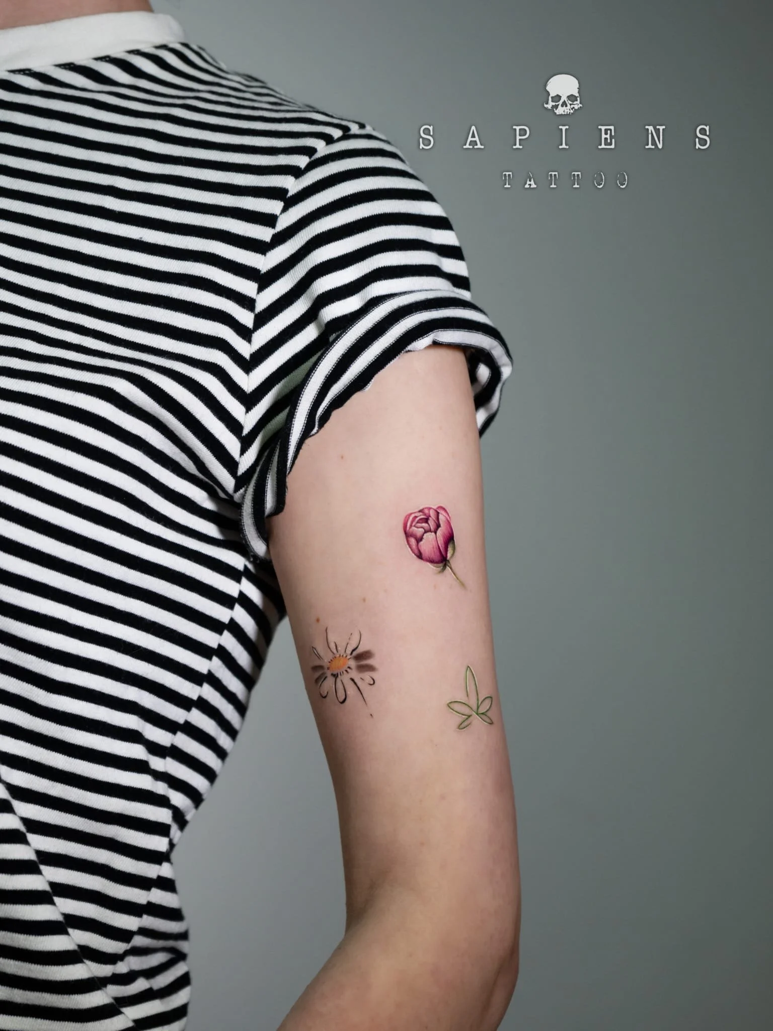 trei tatuaje minimaliste color cu trei floricele pozitionate pe bratul unei femei