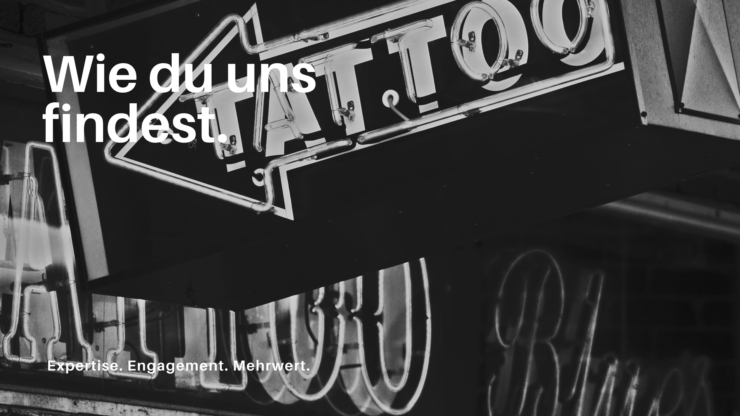 Schwarz-weiß-Bild eines Neonschilds mit dem Text 'TATTOO' und dem deutschen Text 'Wie du uns findest.' sowie den Worten 'Expertise. Engagement. Mehrwert.' am unteren Rand.
