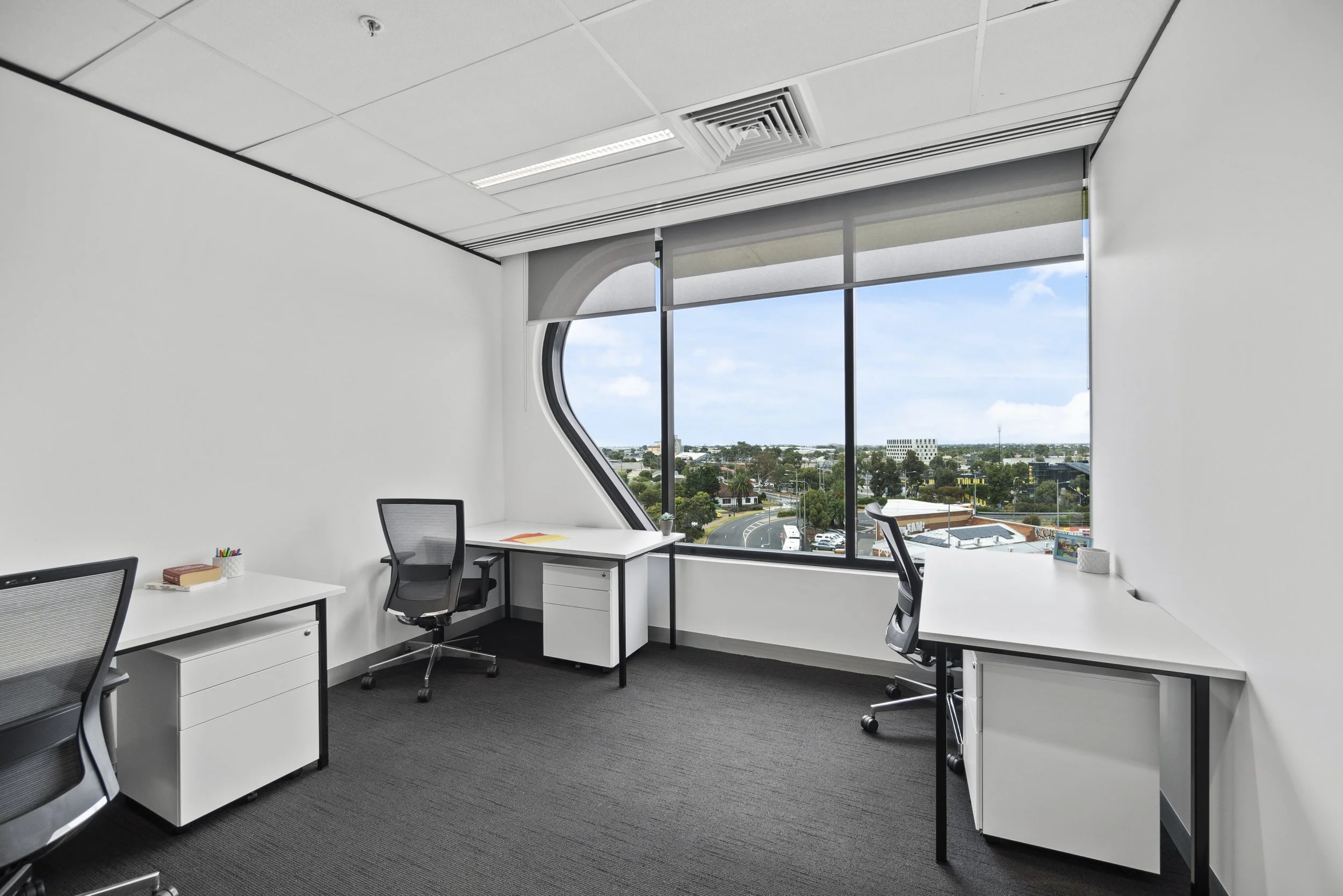 A three desk private office with bright natural light and a wide window