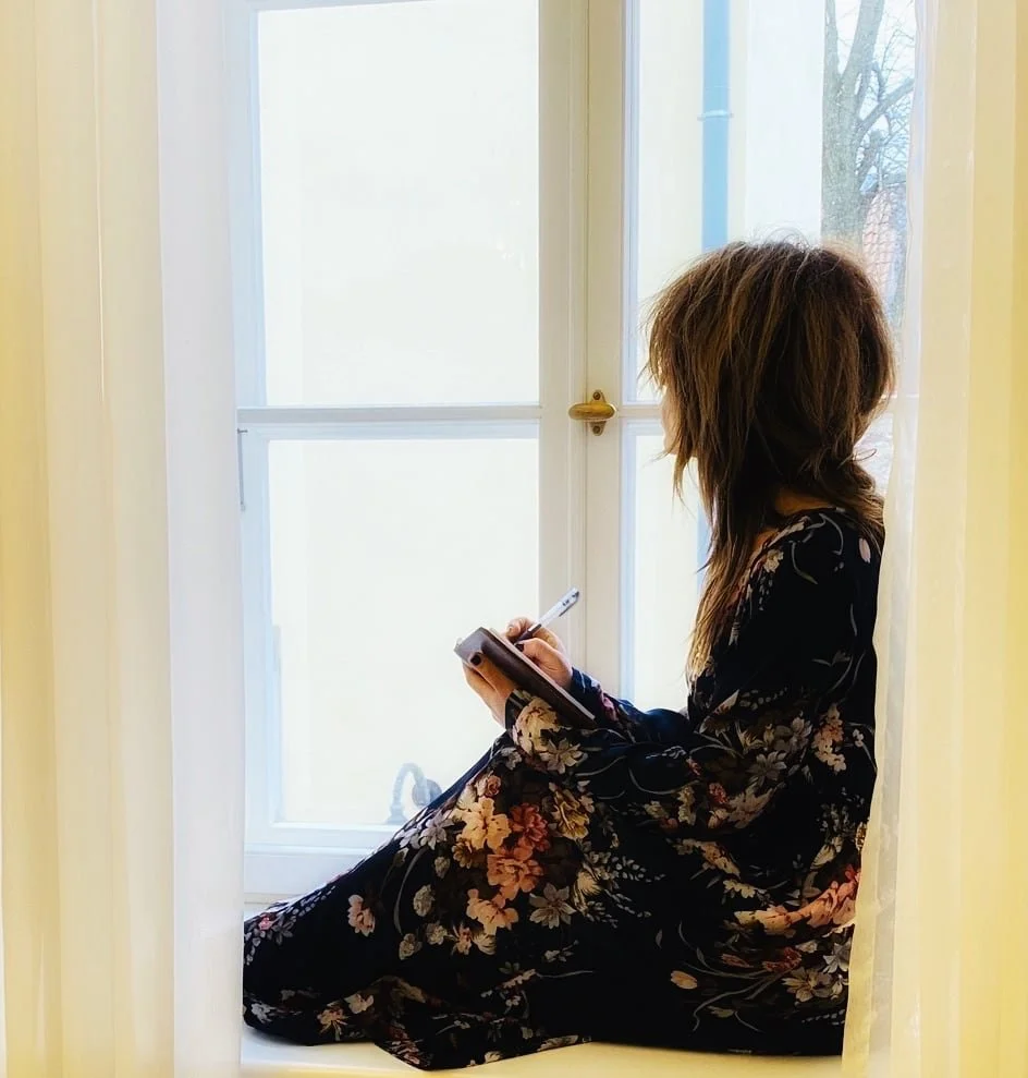 Judi looking out of the window while writing