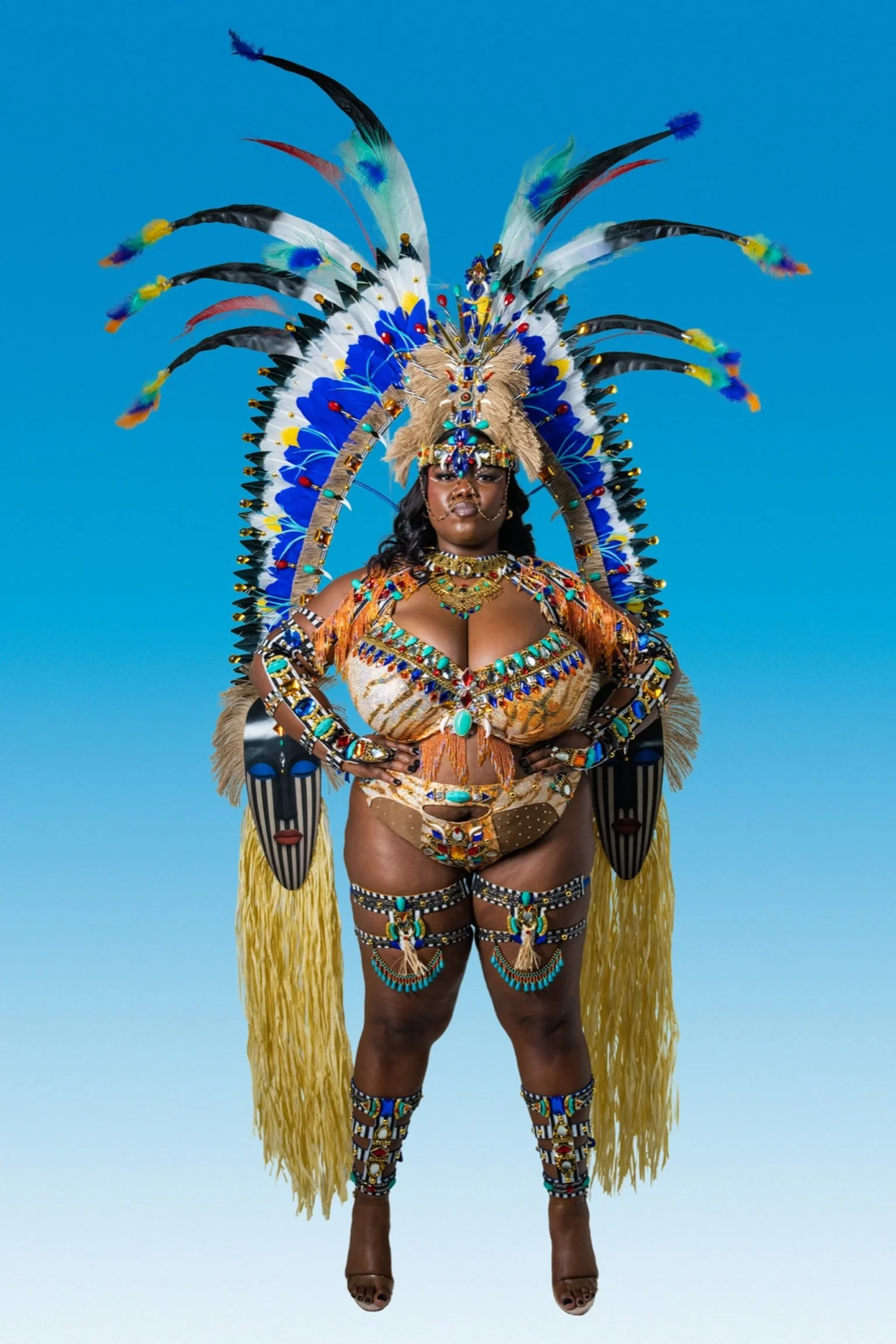 A woman dressed in elaborate, colorful costume with feathers, beads, and jewelry against a blue background.