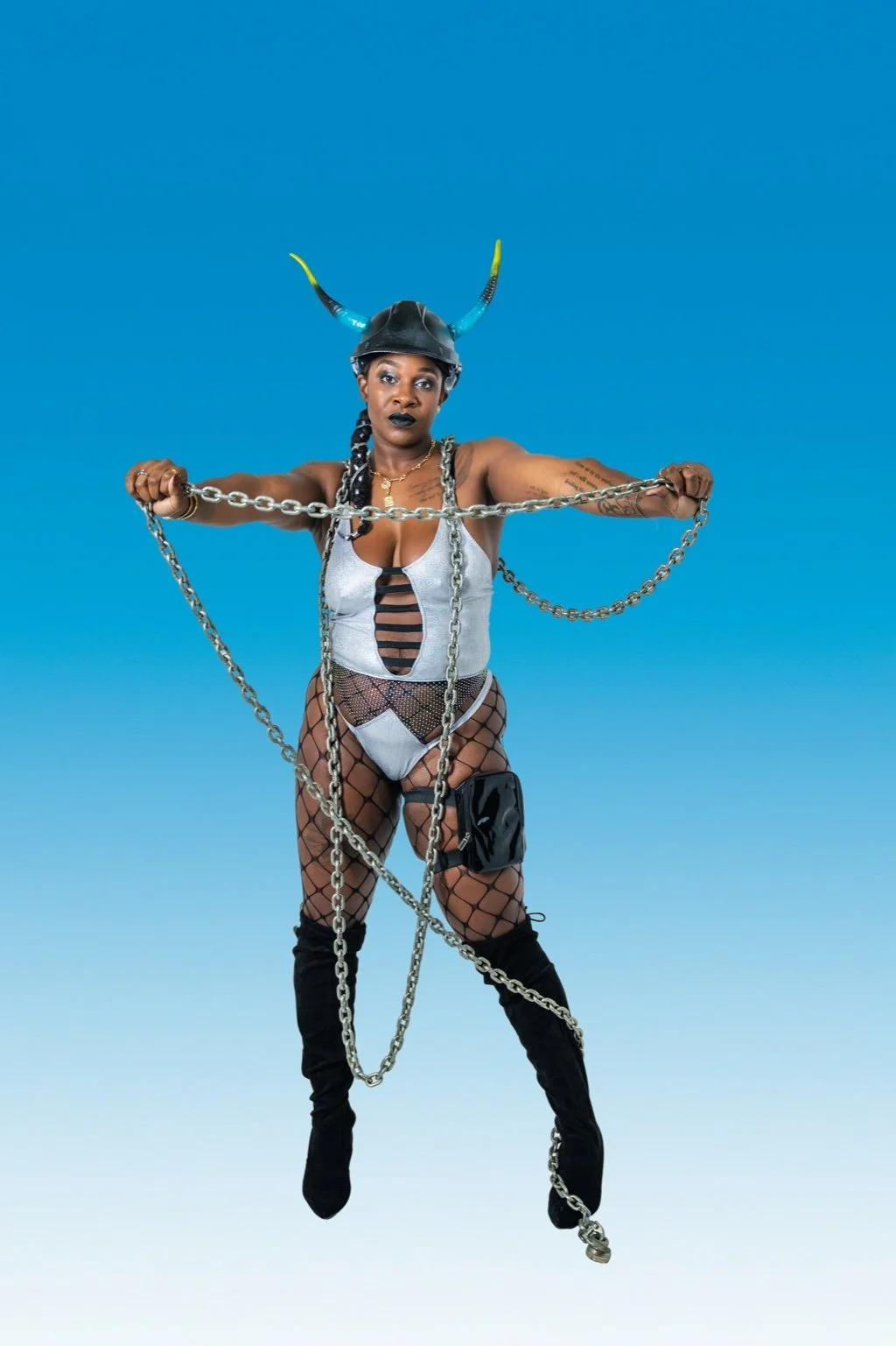 A woman wearing a black helmet with blue and yellow horns, fishnet stockings, a white outfit with black straps, black high boots, and chains, posing against a blue gradient background.