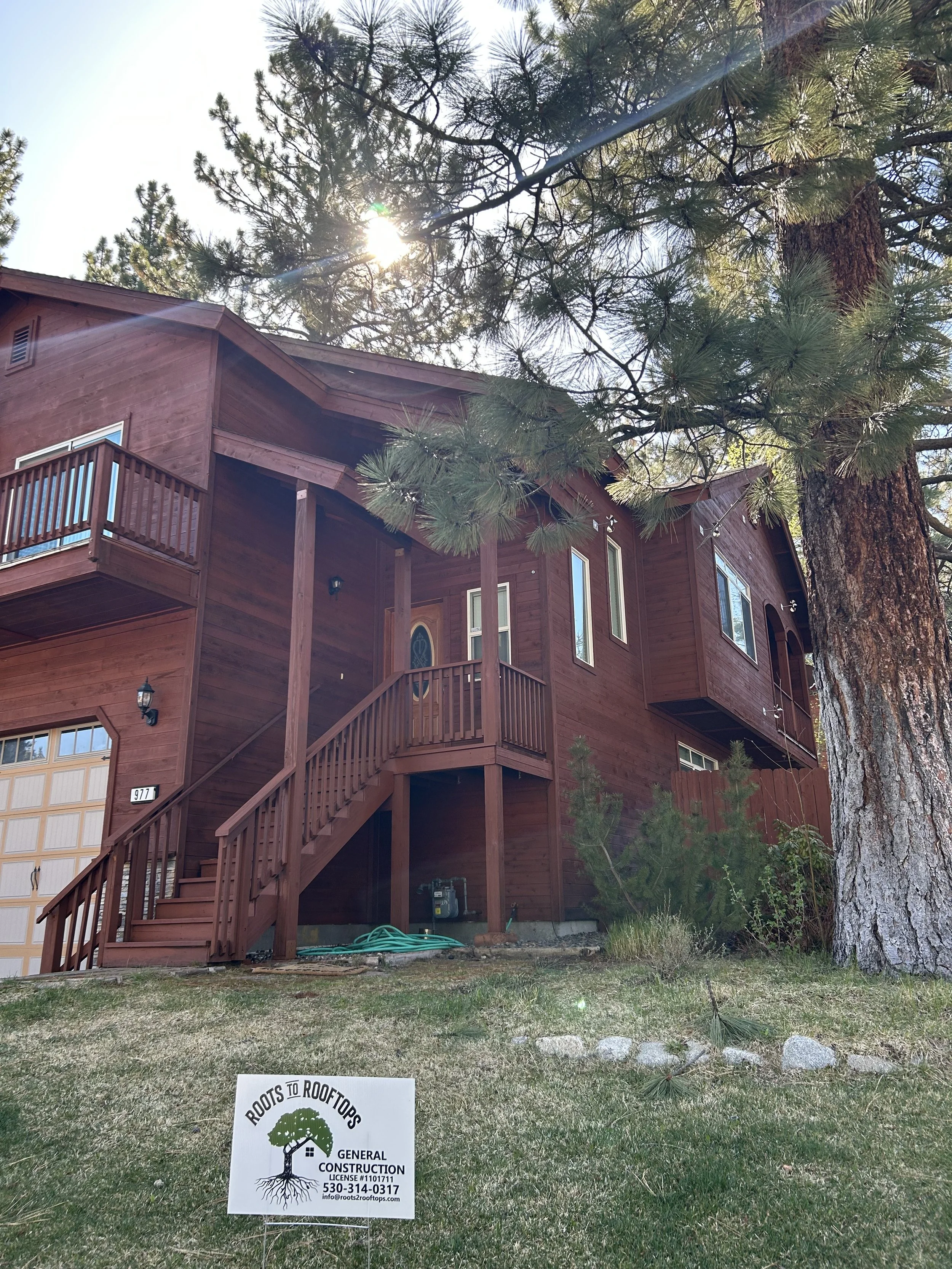 Exterior staining South Lake Tahoe, Roots to Roof Tops General Construction with a tree and house logo and contact information.