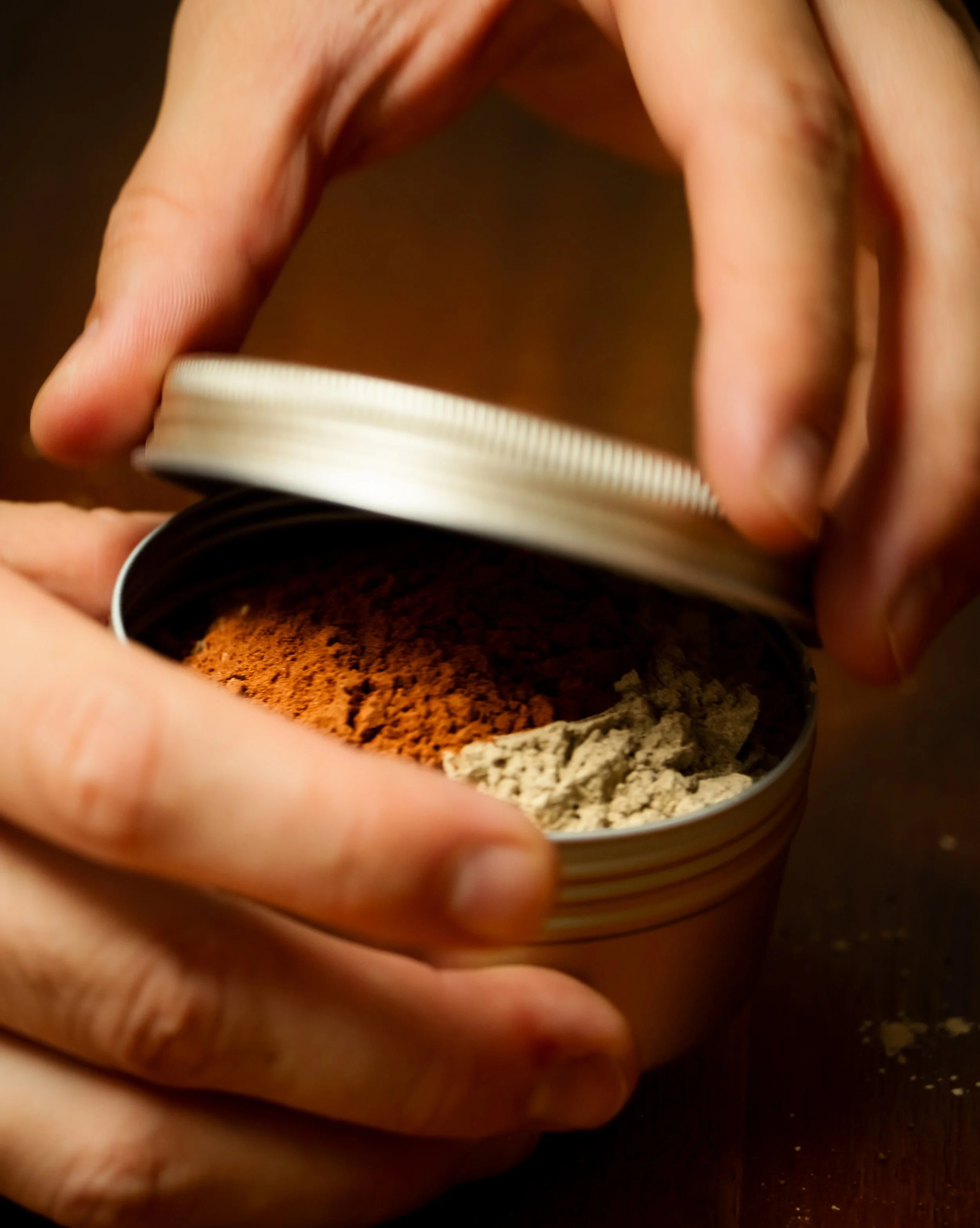 Hands opening a tin of dried Ayurvedic herbs at the Kailua clinic on Oahu.