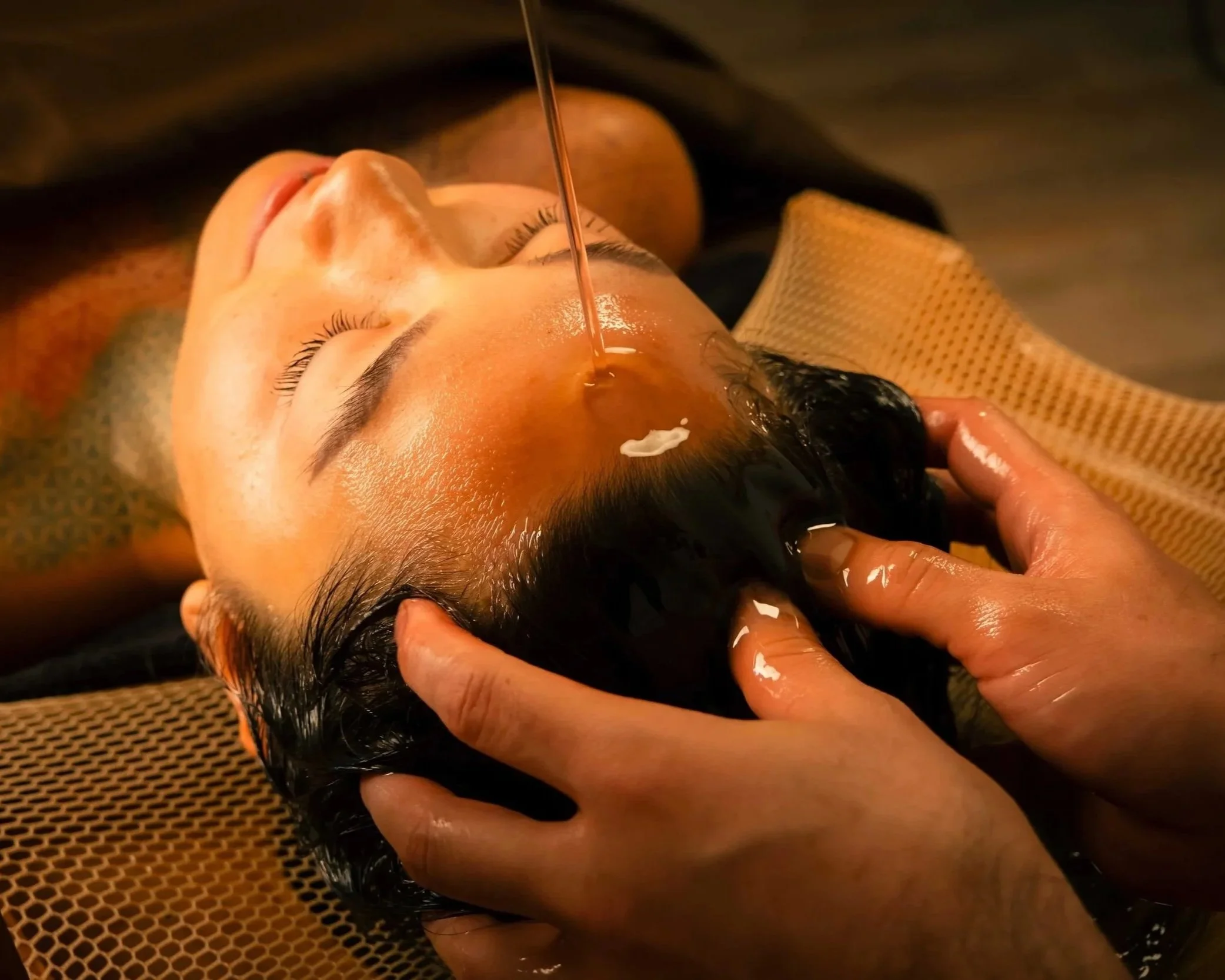 Client receiving shirodhara warm oil treatment massage body treatment
