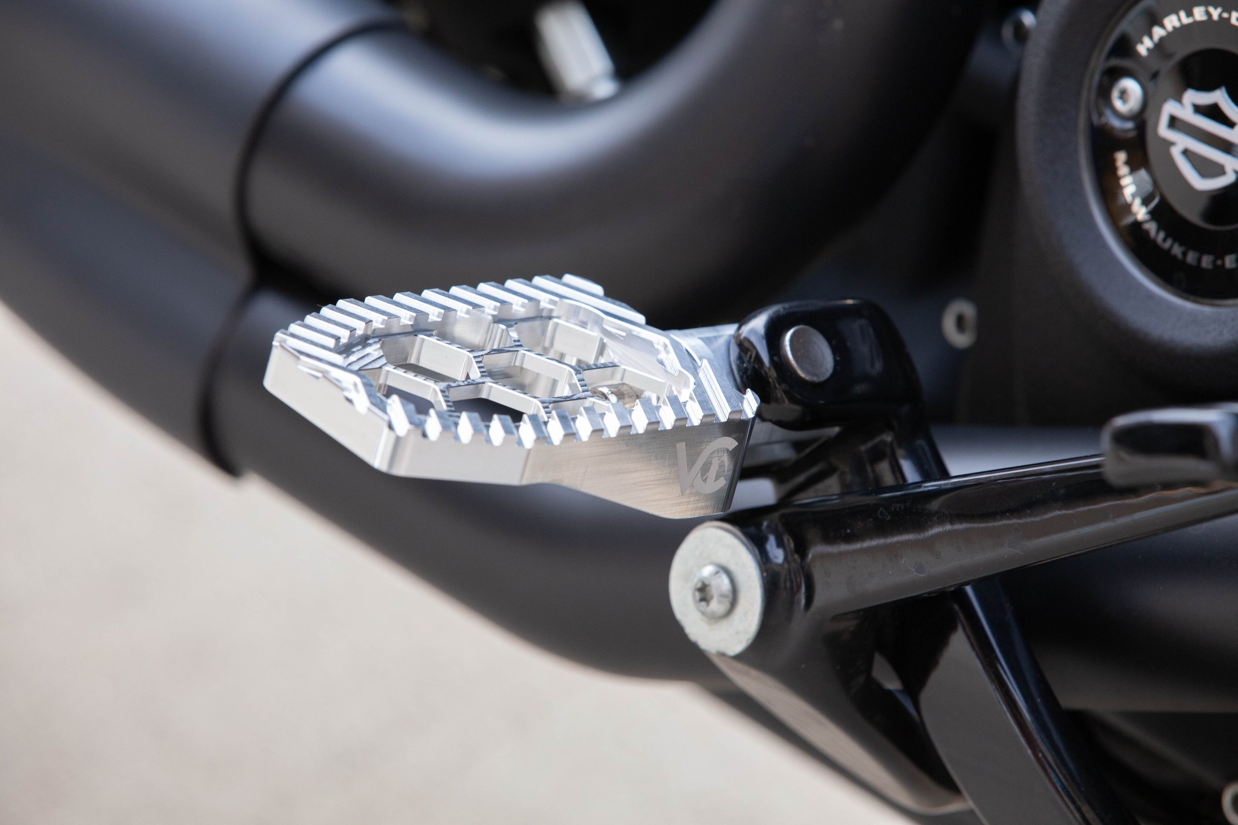 Vengeance Customs rider footpegs for 2018+ Harley-Davidson Softail in Raw Finish, installed on motorcycle