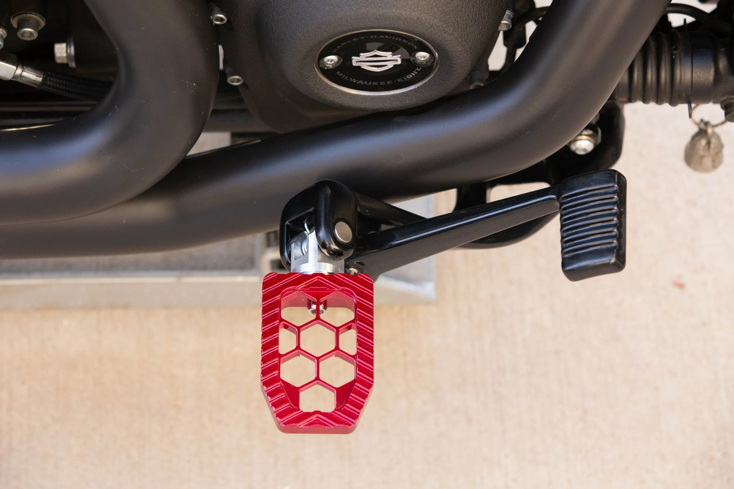 Vengeance Customs rider footpegs for 2018+ Harley-Davidson Softail in Red Ritual Finish, installed on motorcycle