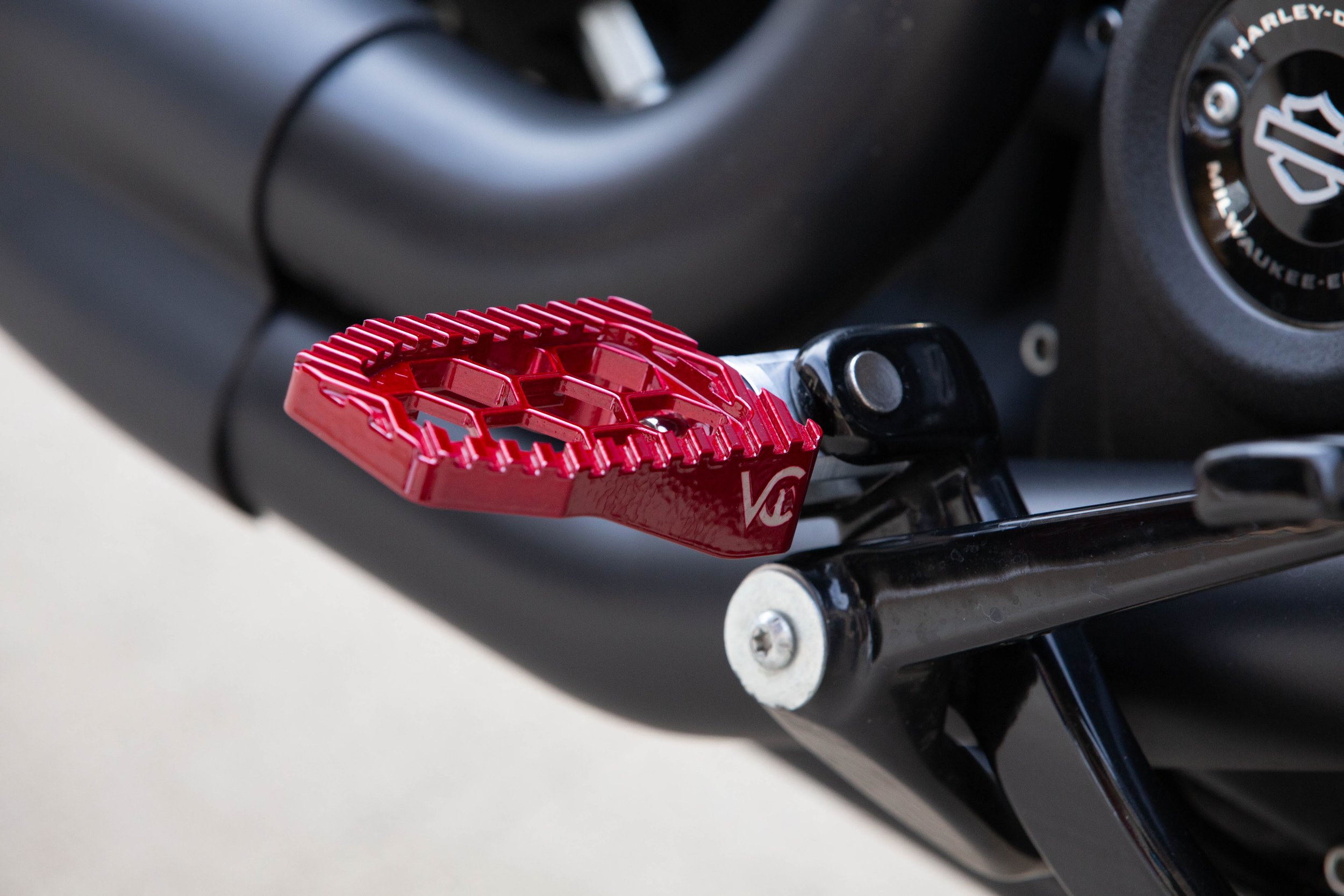 Vengeance Customs rider footpegs for 2018+ Harley-Davidson Softail in Red Ritual Finish, installed on motorcycle