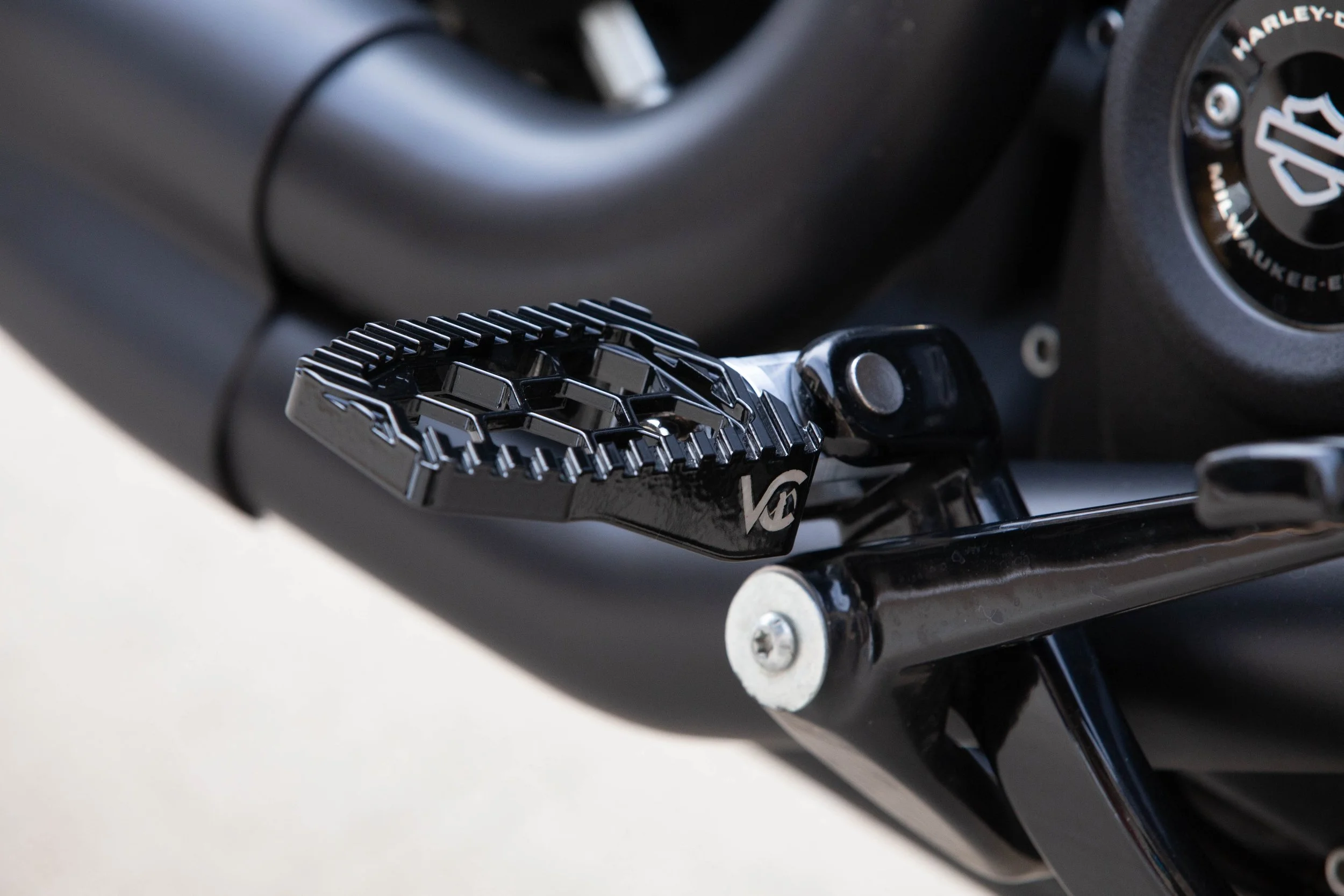 Vengeance Customs rider footpegs for 2018+ Harley-Davidson Softail in Black Eclipse, installed on motorcycle