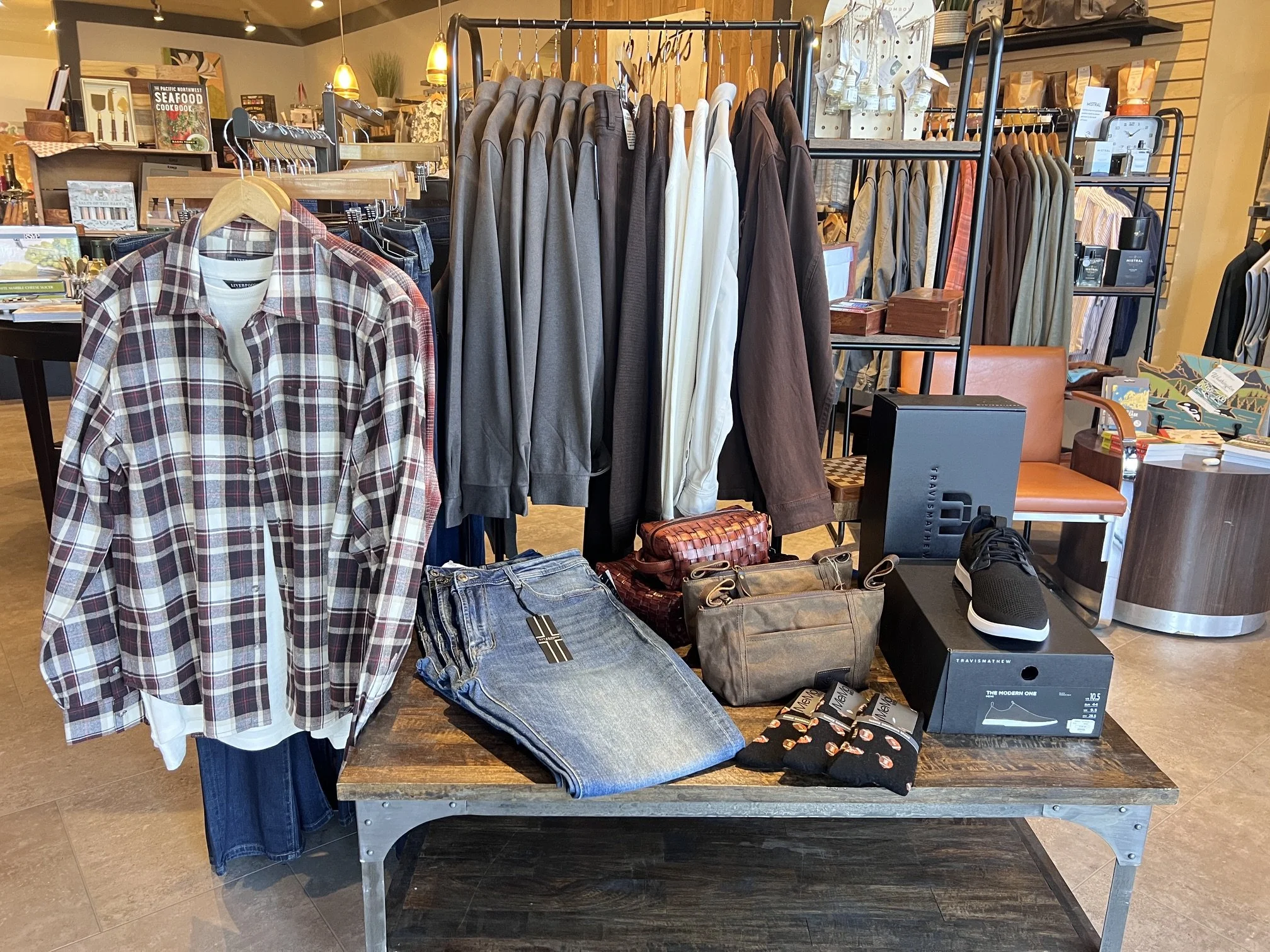 Clothing store interior with shirts, jackets, candles, and accessories on display.