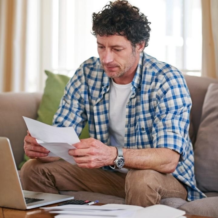 1. Man reviewing physical therapy bills and treatment costs at home.