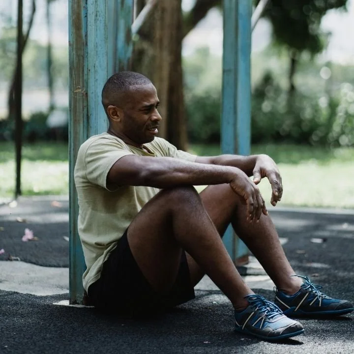 Runner sitting on ground resting after outdoor workout.