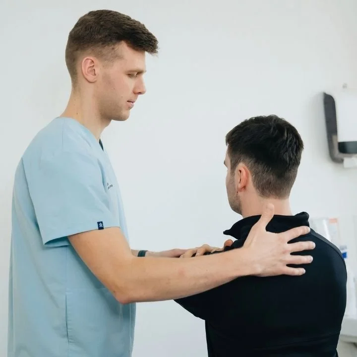 Physical therapist assessing a patient's shoulder mobility during an examination.